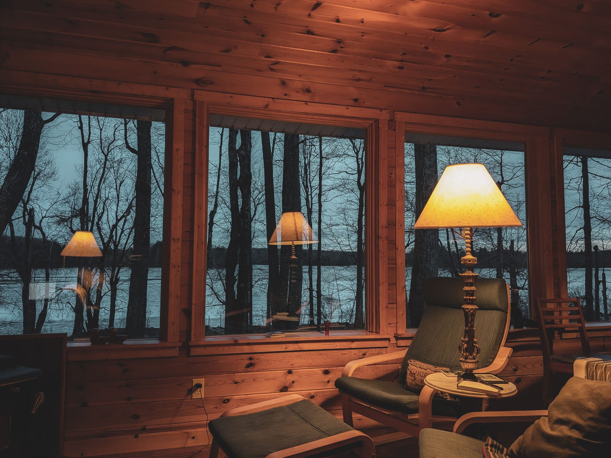 Warm, peaceful cabin interior with glowing lights and lake view, perfect for relaxation and nature enjoyment.