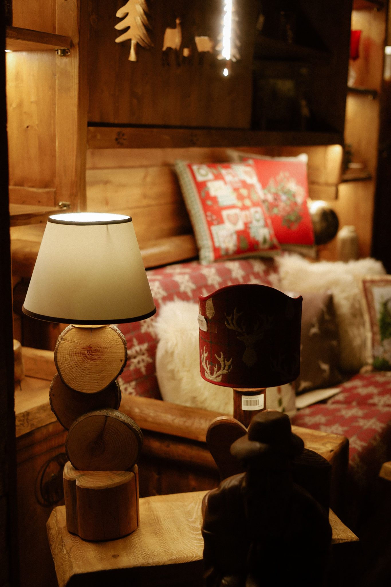 Warm, rustic cabin interior featuring pillows, throw blankets, and soft lighting.