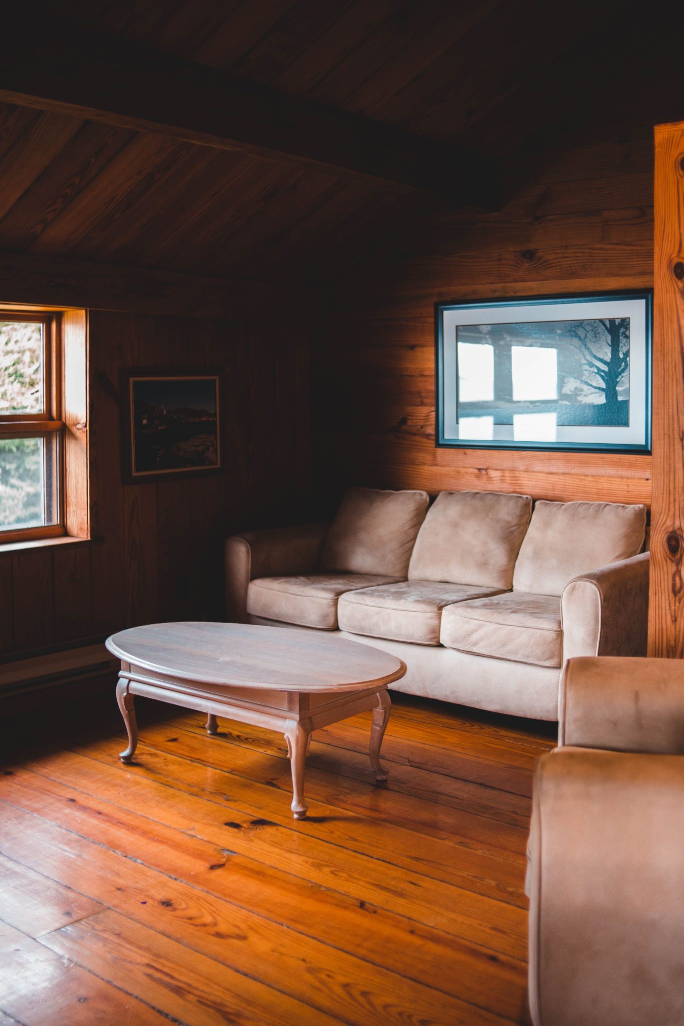 Warm wooden interior with a comfortable sofa and a coffee table by the window.