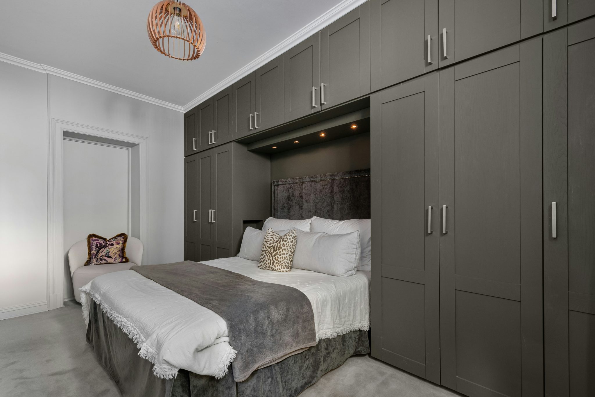 A bedroom with a bed, cabinets, and a chandelier