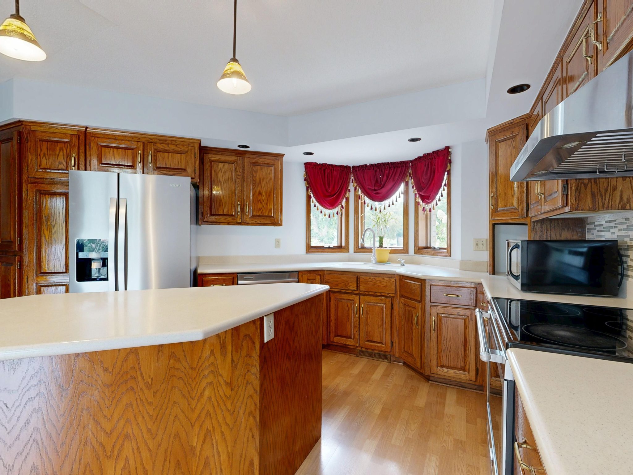 A bright, modern kitchen featuring wooden cabinets, island, and stainless steel appliances.