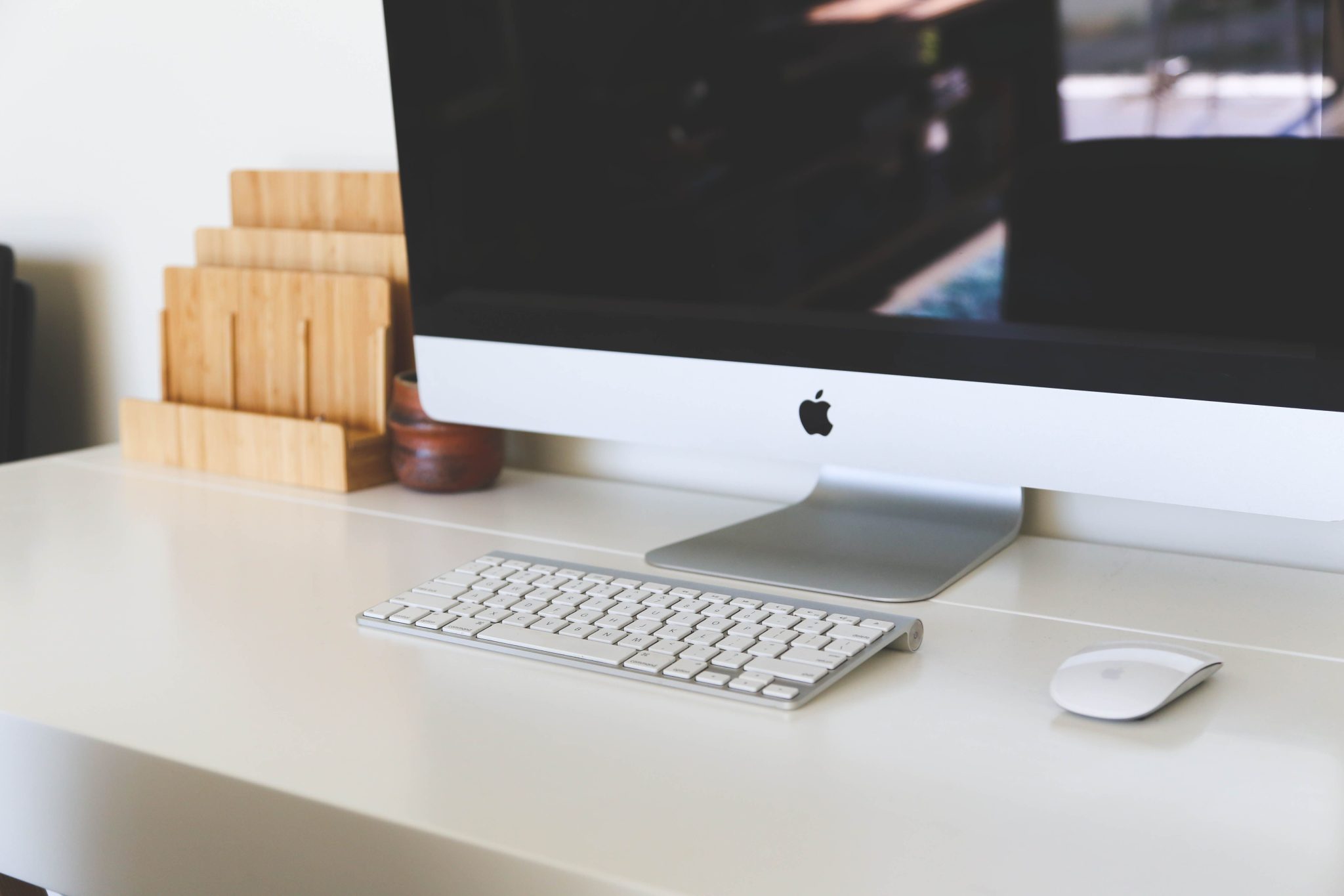 A clean and modern home office workspace featuring an iMac, keyboard, and magic mouse on a minimalist desk.