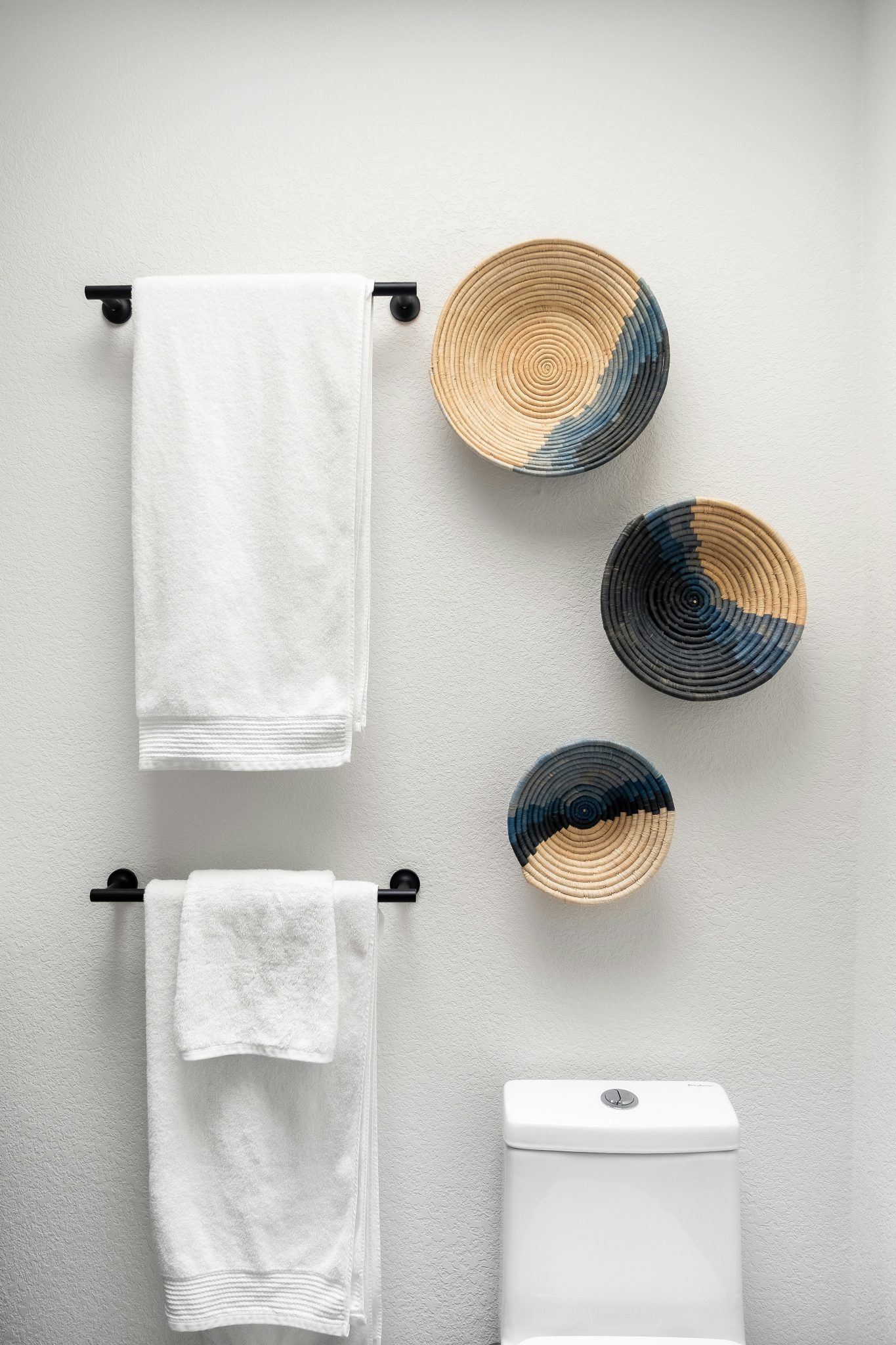 A minimalist white washroom with a serene ambiance. A fluffy white towel hangs on a towel hanger.
