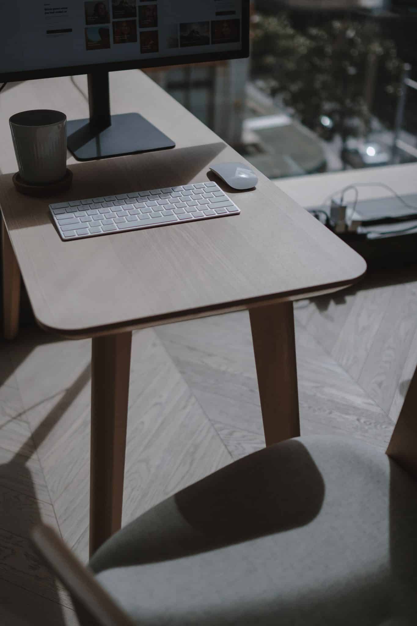 A stylish and minimalist home office setup featuring a desk with a keyboard and monitor, set in a well-lit room.
