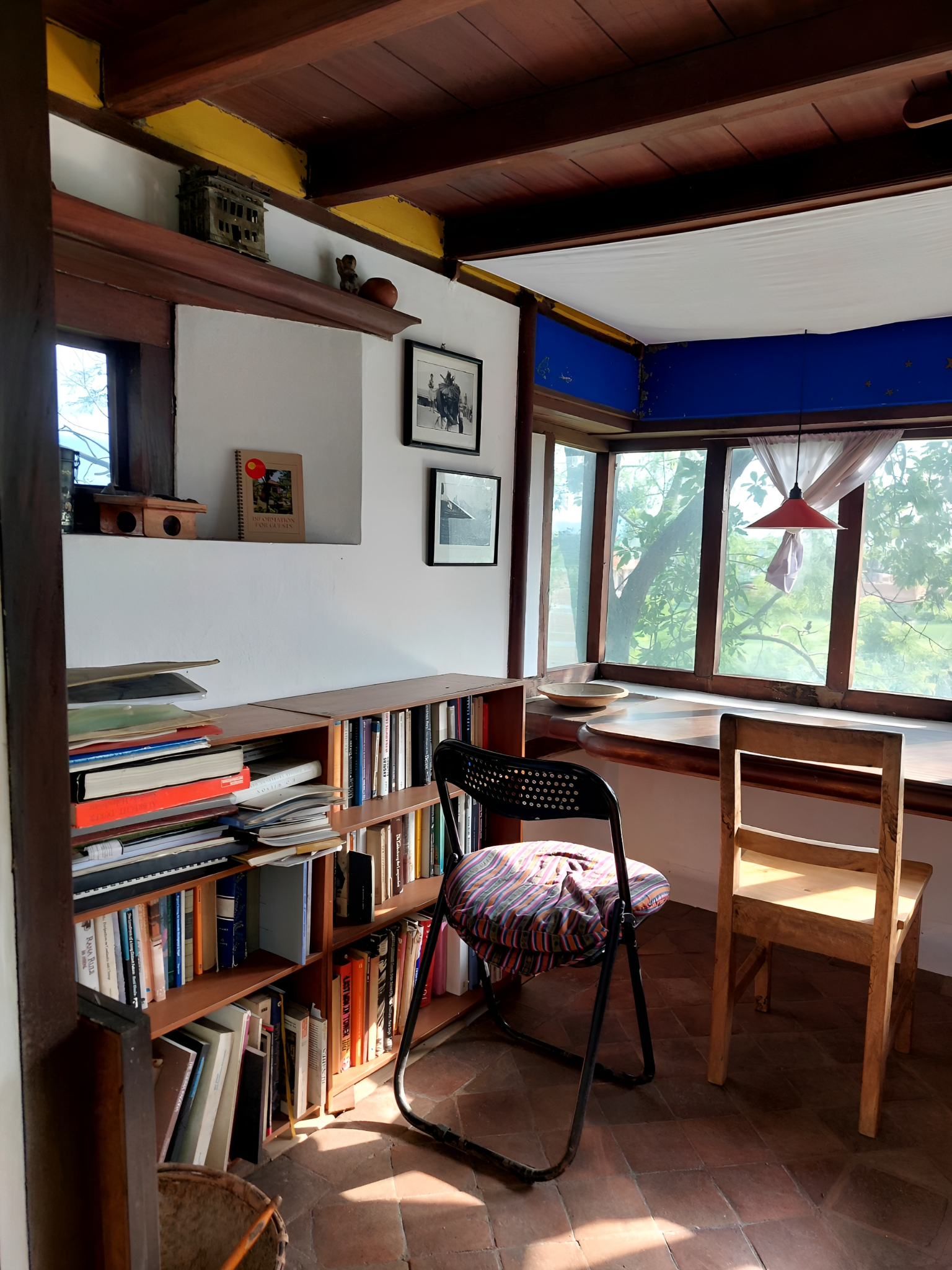 A well-lit home office with bookshelves, chairs, and large windows offering natural light.