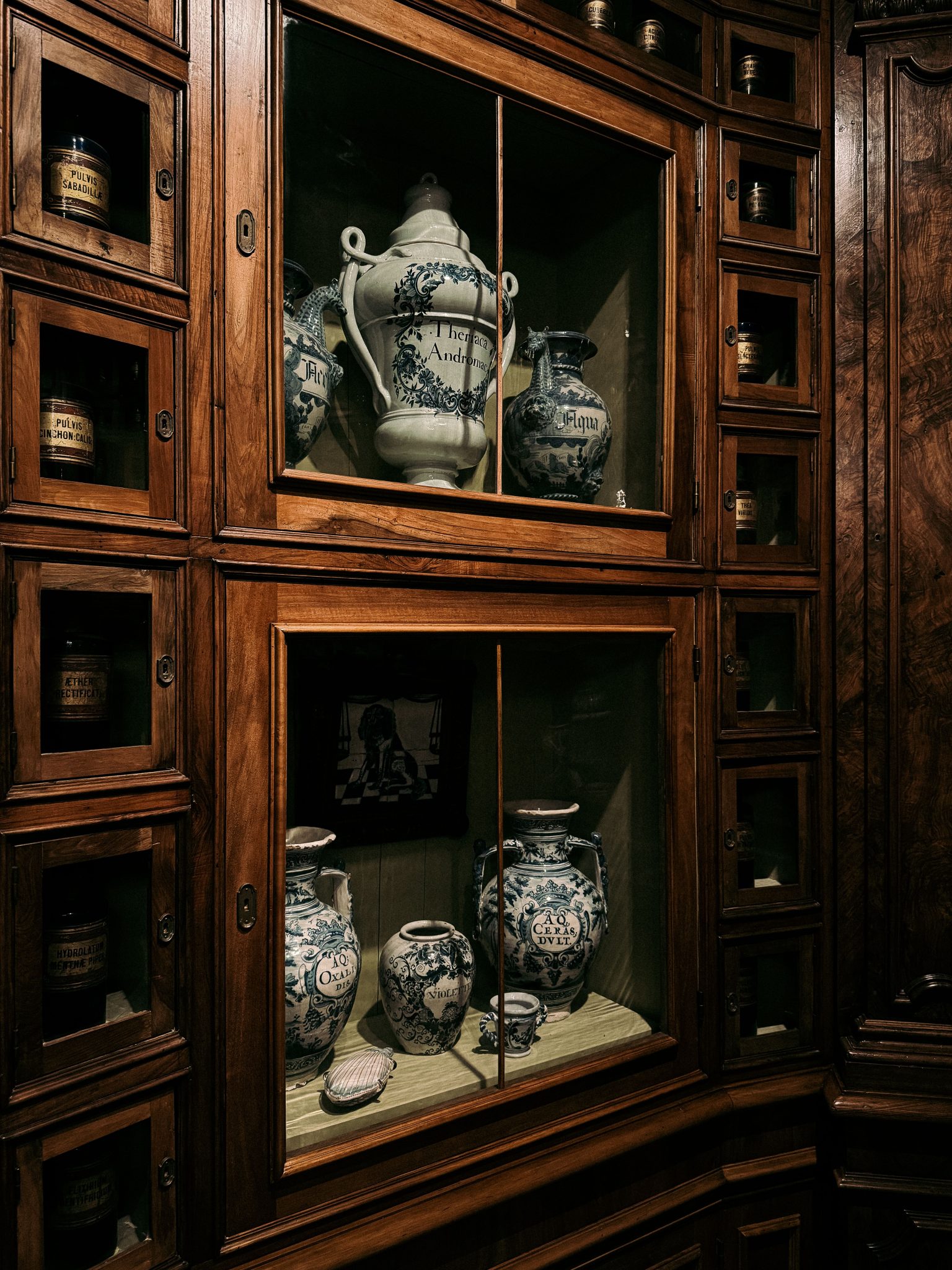Antique apothecary jars displayed in a traditional wooden cabinet from an old pharmacy.