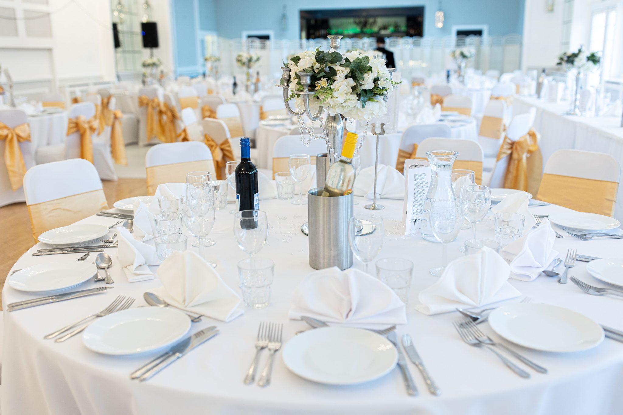 Beautifully set wedding reception with floral centerpieces and white tablecloths.