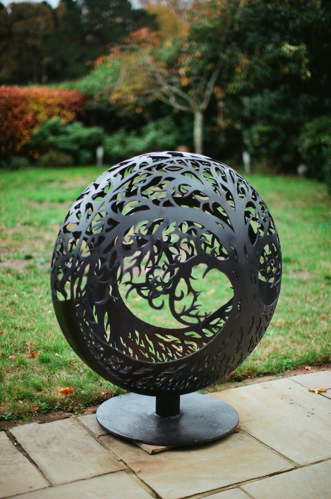 Black metal sphere sculpture with tree design