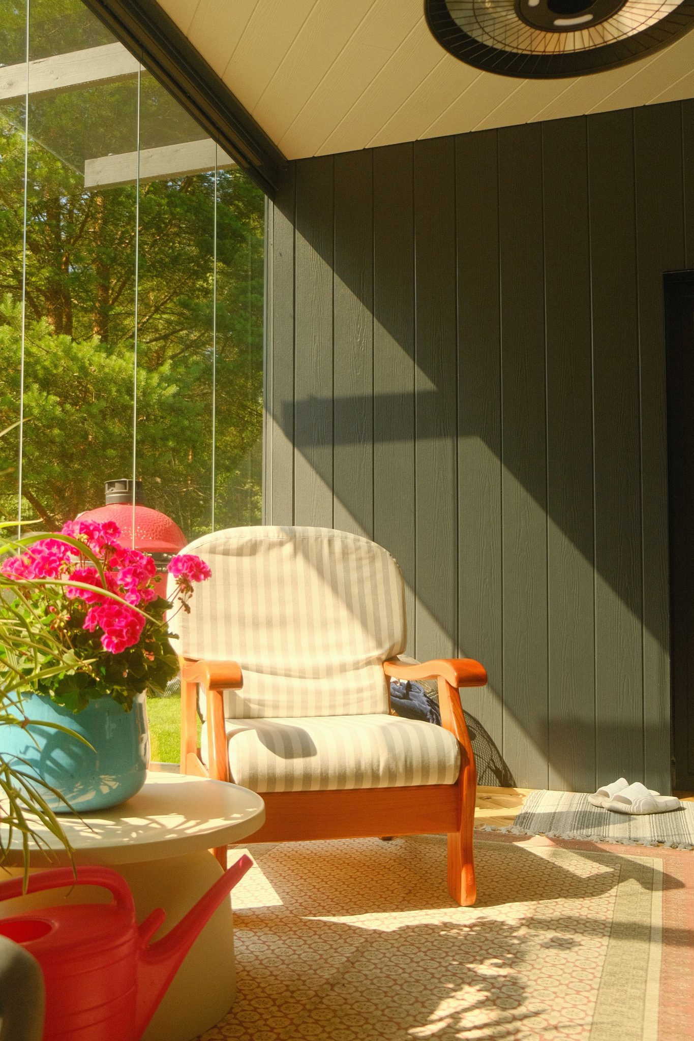 Bright sunlit porch with a cozy chair and vibrant flowers, perfect for relaxation.