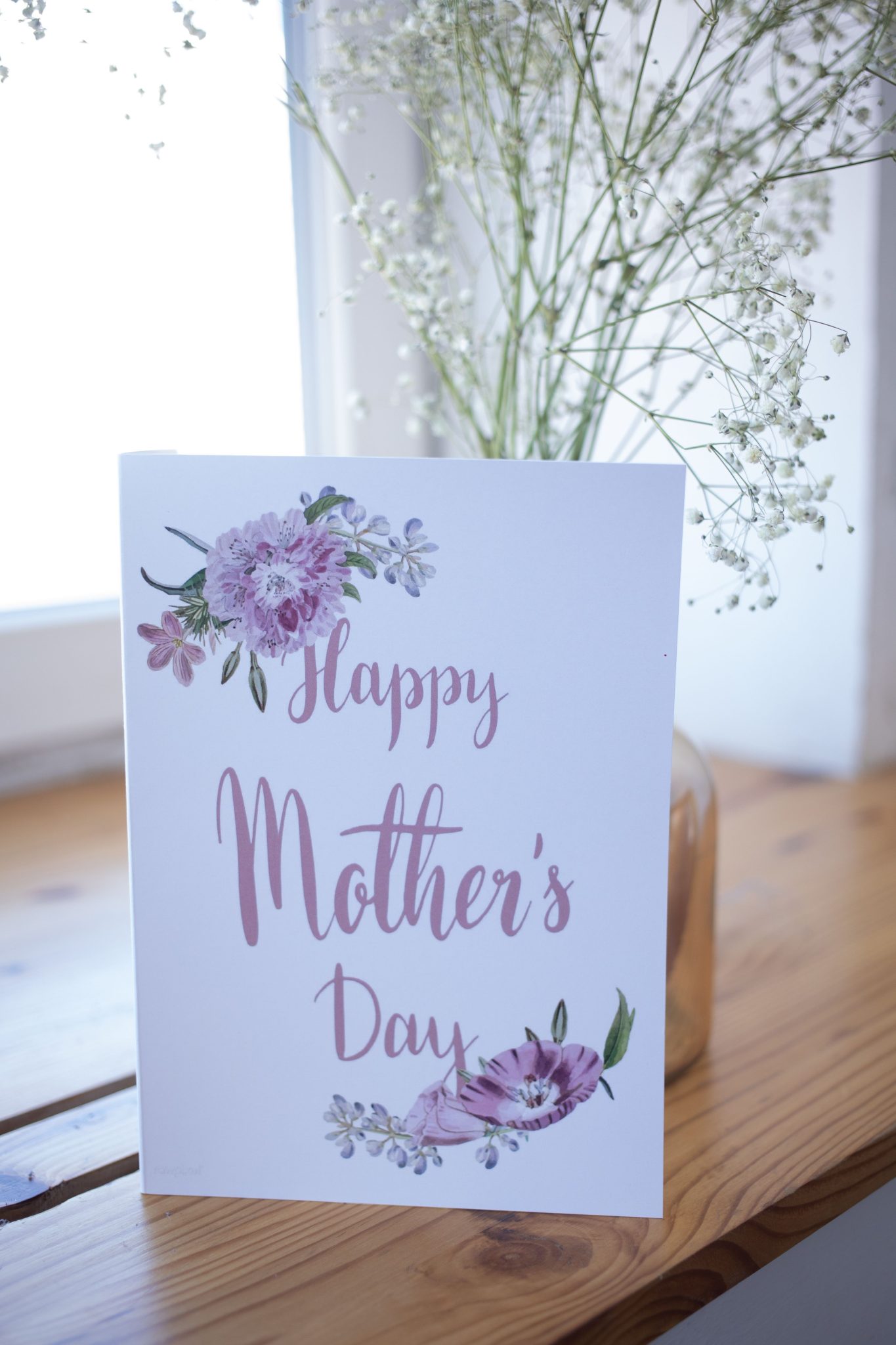 Charming Mother's Day card featuring floral illustrations, placed on a wooden table.