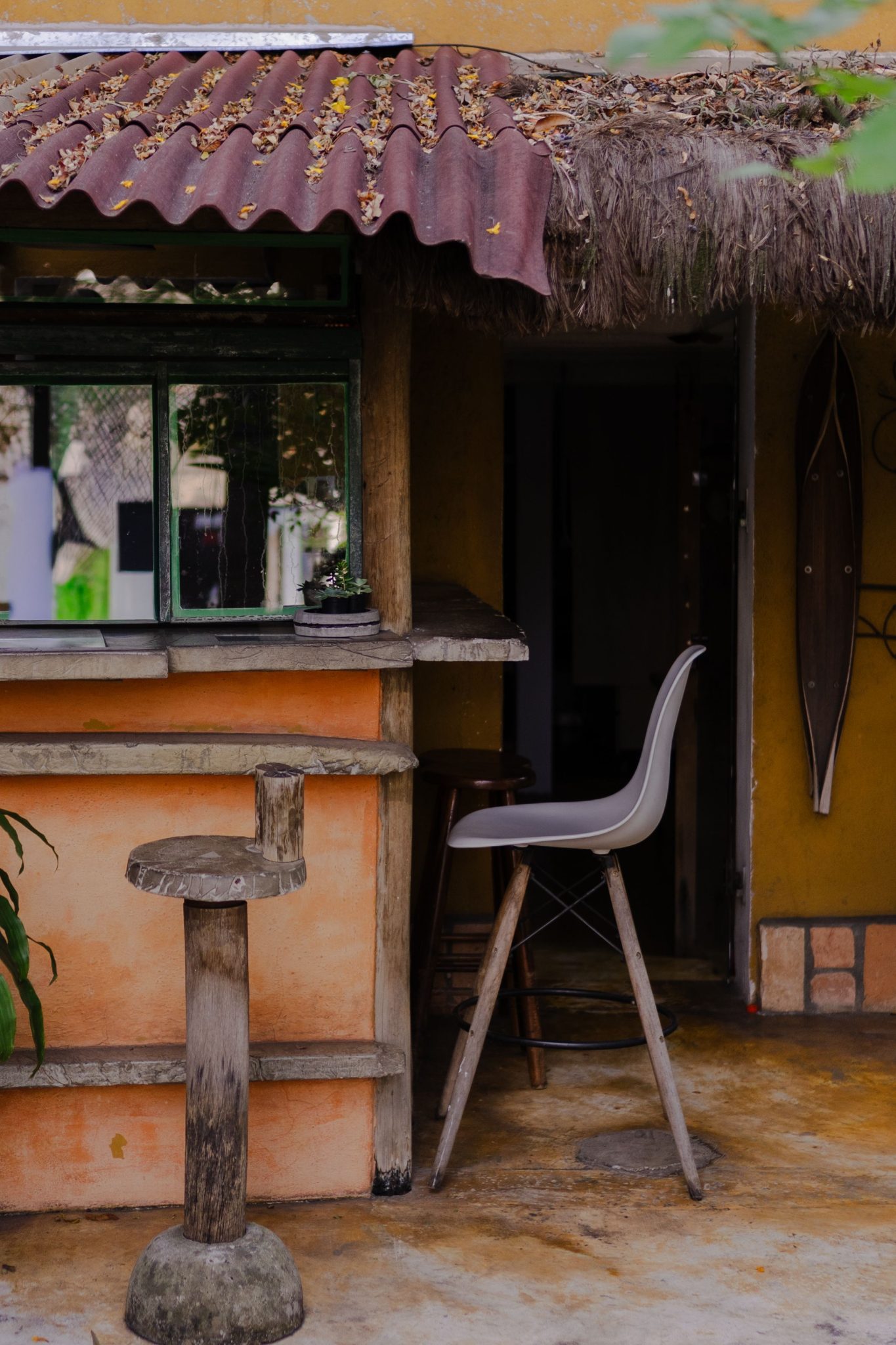 Charming rustic outdoor bar with wooden stools and thatched roof, evoking a cozy, tropical vibe.