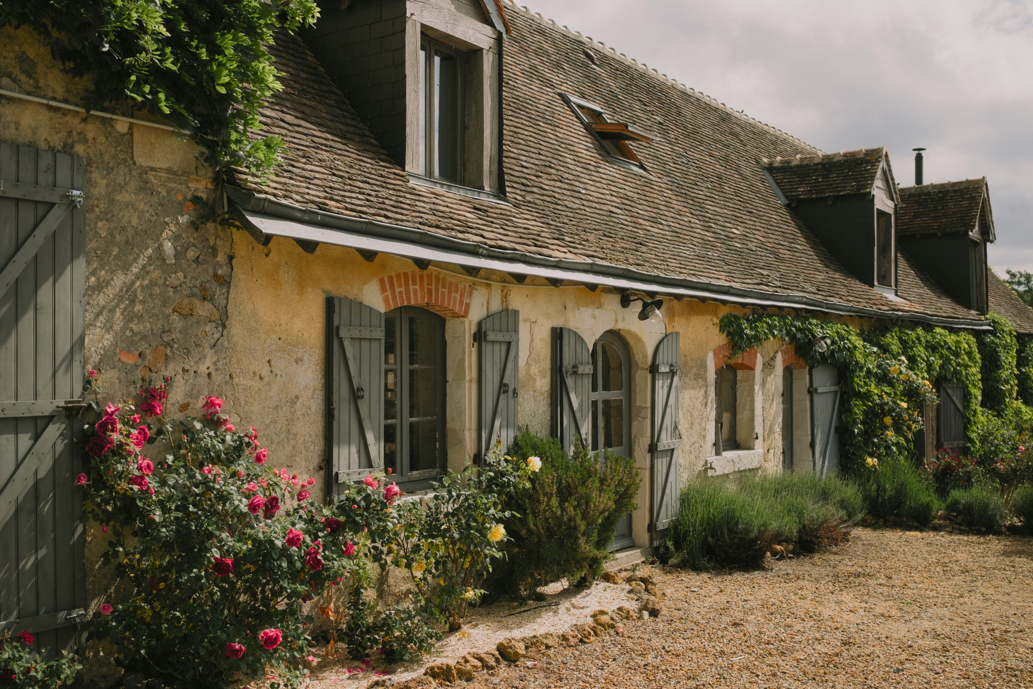 Charming stone cottage with blooming roses and shutters.
