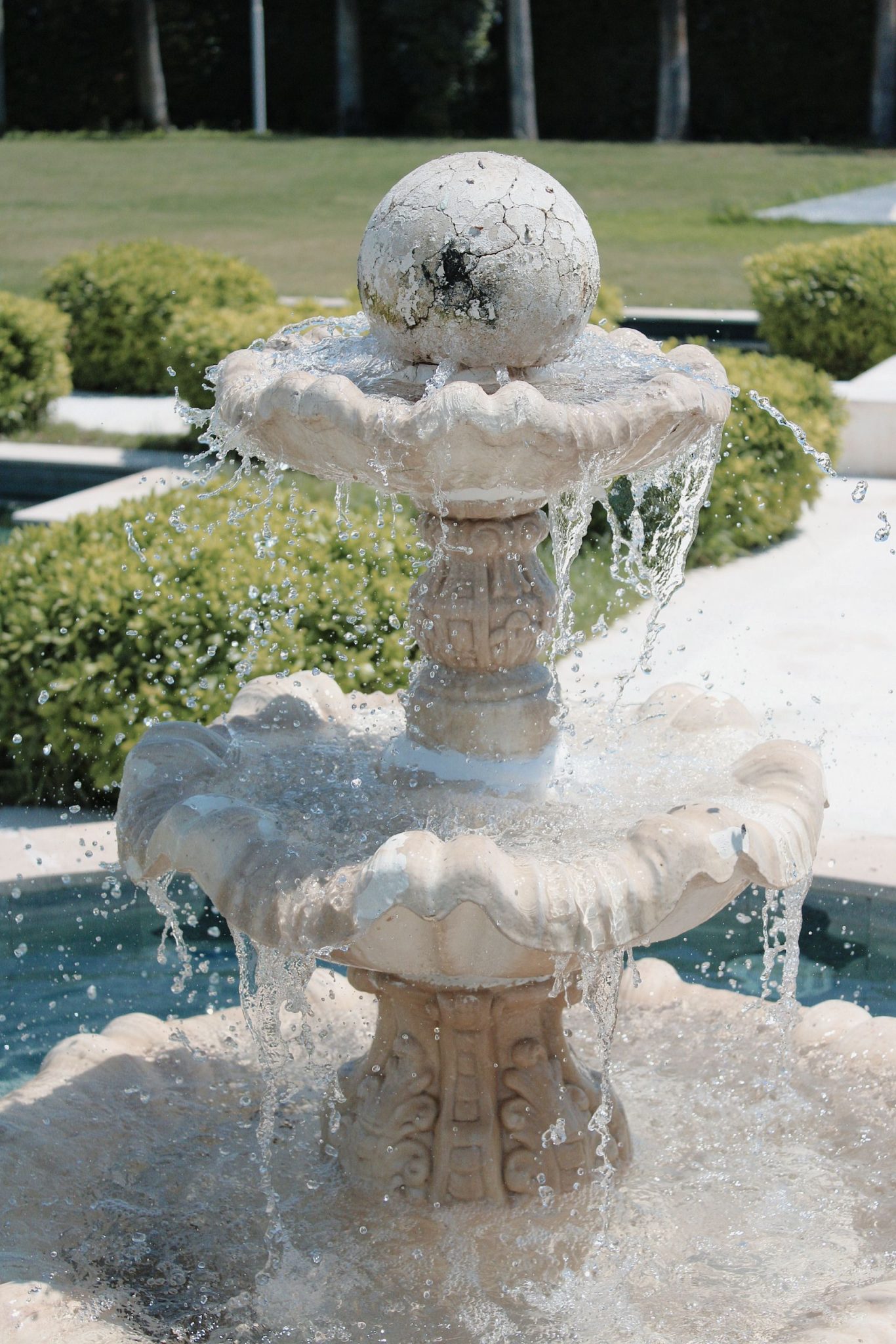 Close-up of a classic stone fountain with splashing water in a sunny garden.