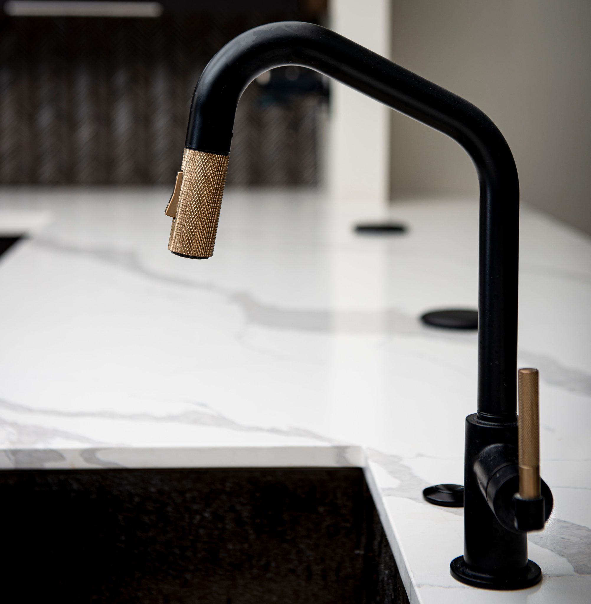 Close-up view of a modern black and gold faucet in a sleek kitchen setting, showcasing elegance.