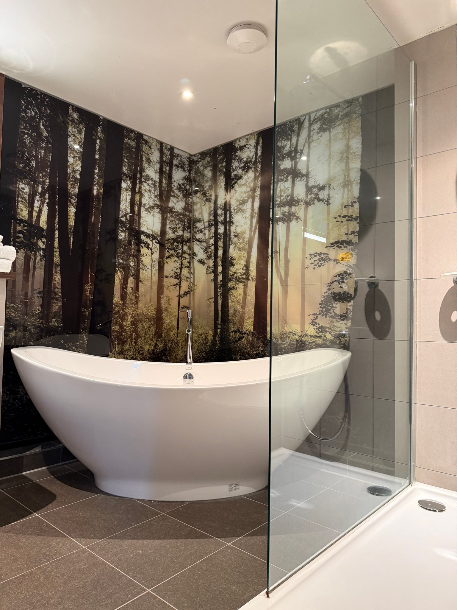 Contemporary bathroom featuring a freestanding tub and a forest-themed wall mural for a nature-inspired ambiance.