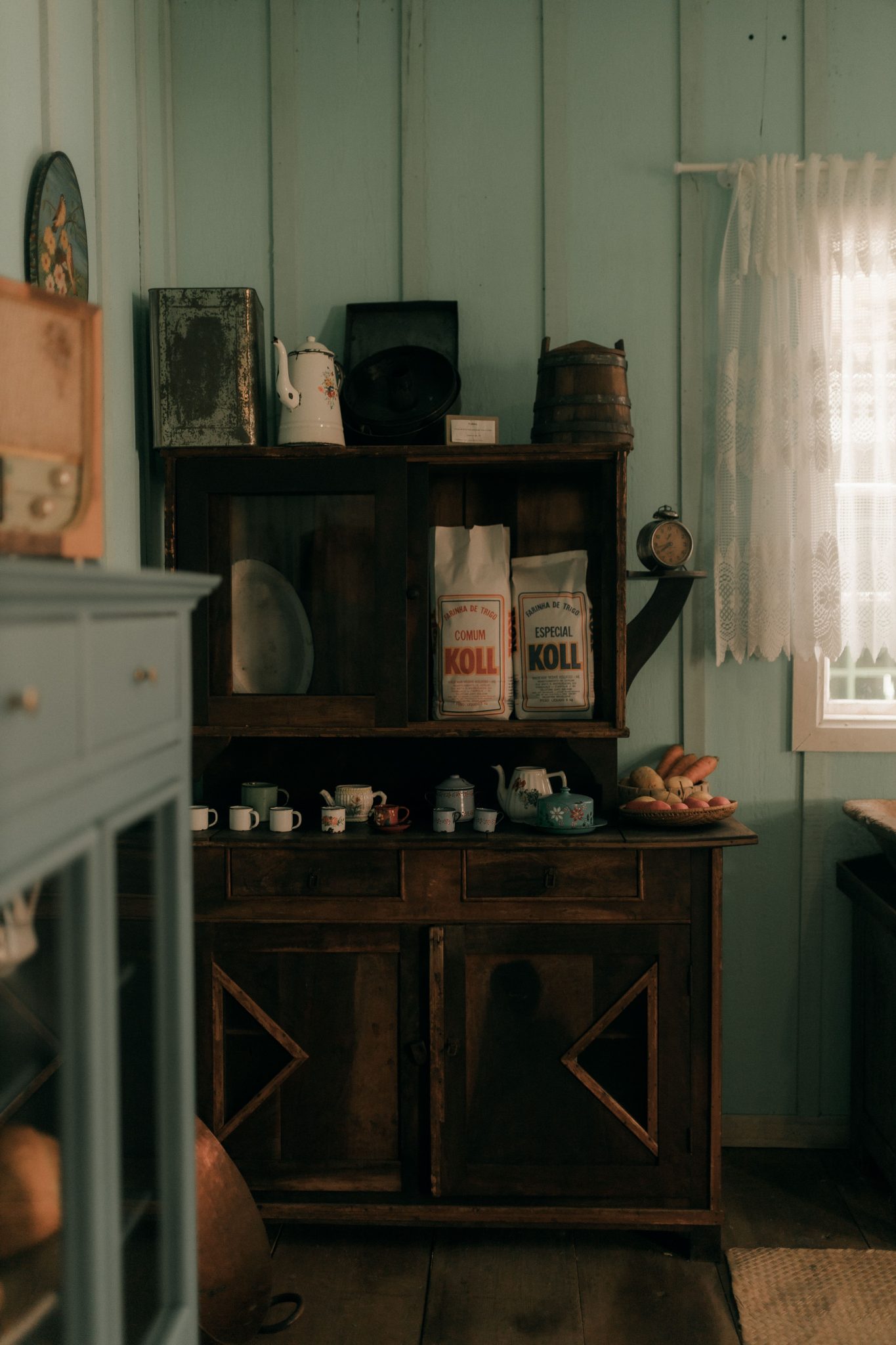 Cozy vintage kitchen interior featuring a rustic wooden cabinet filled with kitchenware and decorative items.