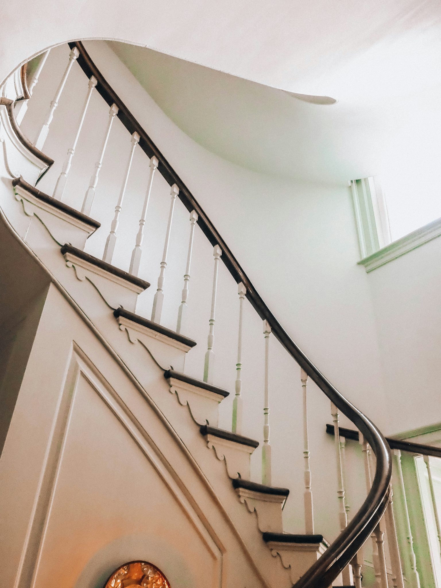 Elegant curving staircase with dark wood and white balusters.