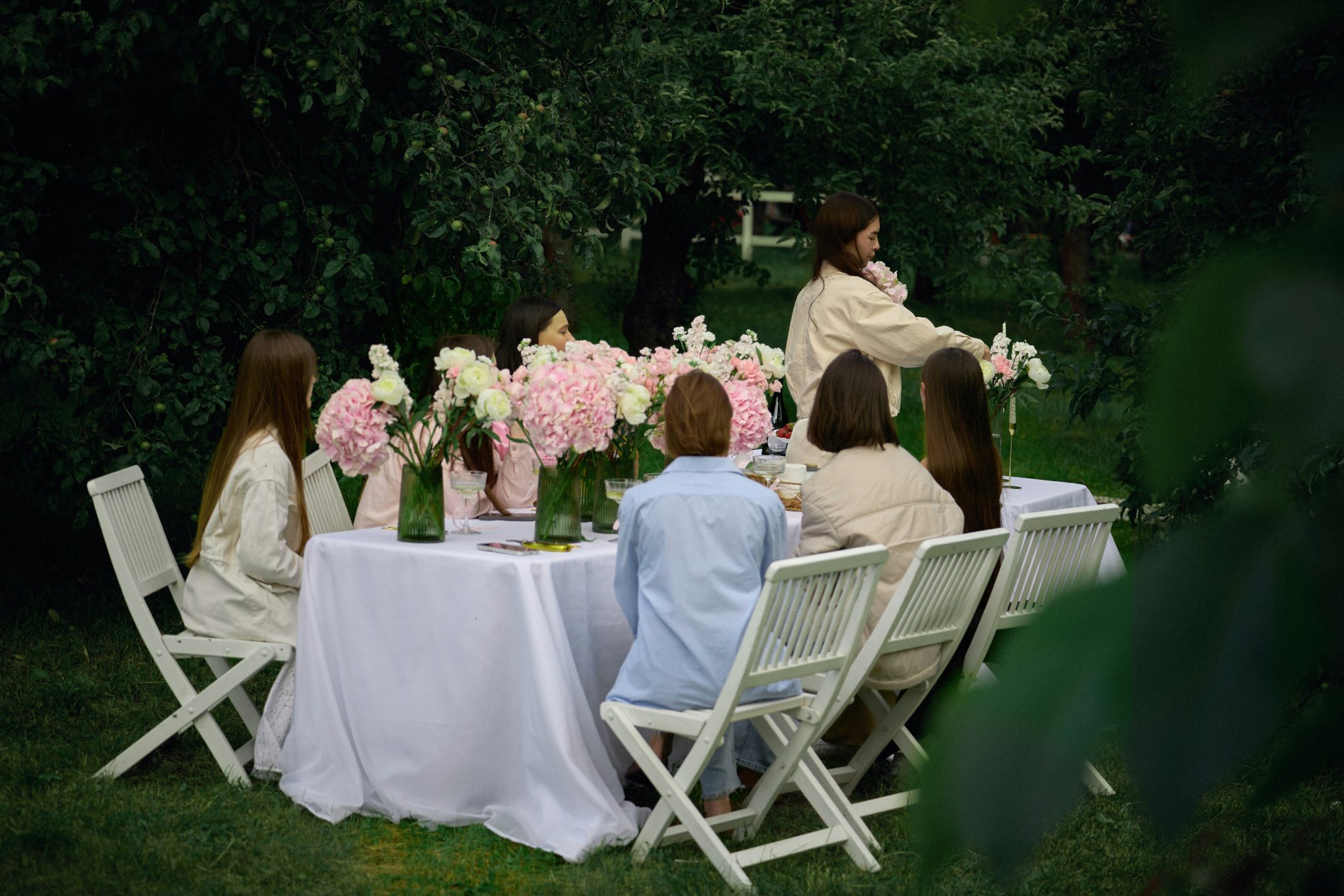Elegant garden table setting with blush pink peonies and soft summer light. A romantic outdoor dining scene perfect for weddings, garden parties, and luxury entertaining.