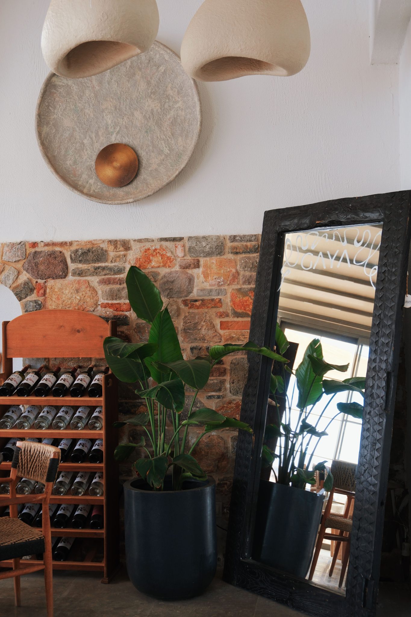 Elegant indoor setup featuring a wine rack, large mirror, and houseplants for a cozy atmosphere.