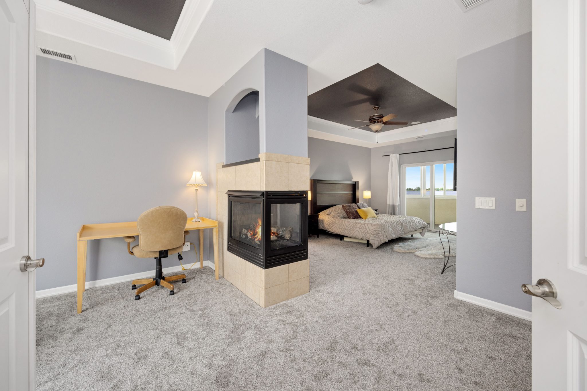 Elegant modern bedroom featuring a cozy fireplace and minimalist design with desk setup.