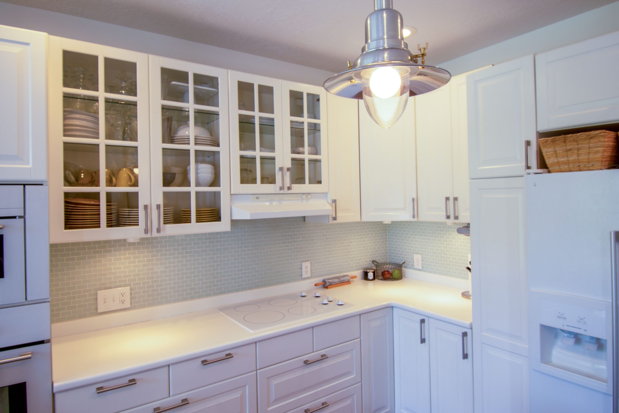 Elegant white kitchen with glass cabinets and modern appliances in an open layout.