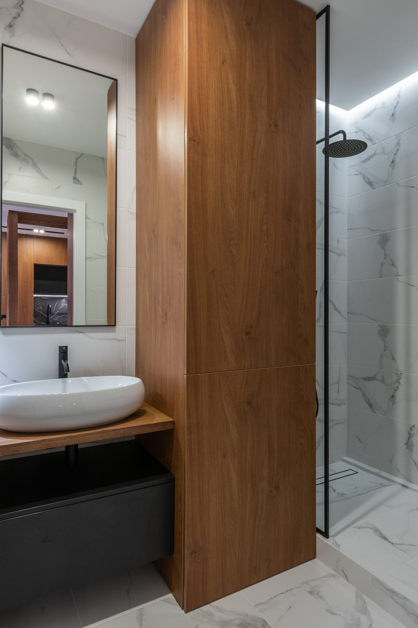 Interior of contemporary bathroom with wooden cupboard placed between sink and shower cabin