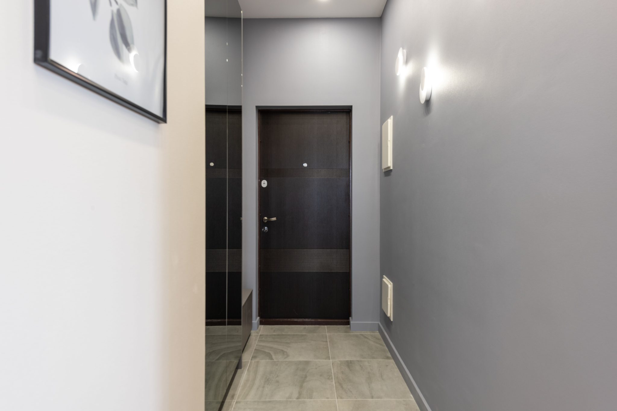 Interior of light empty hallway with white walls and parquet floor furnished with closet with mirror doors