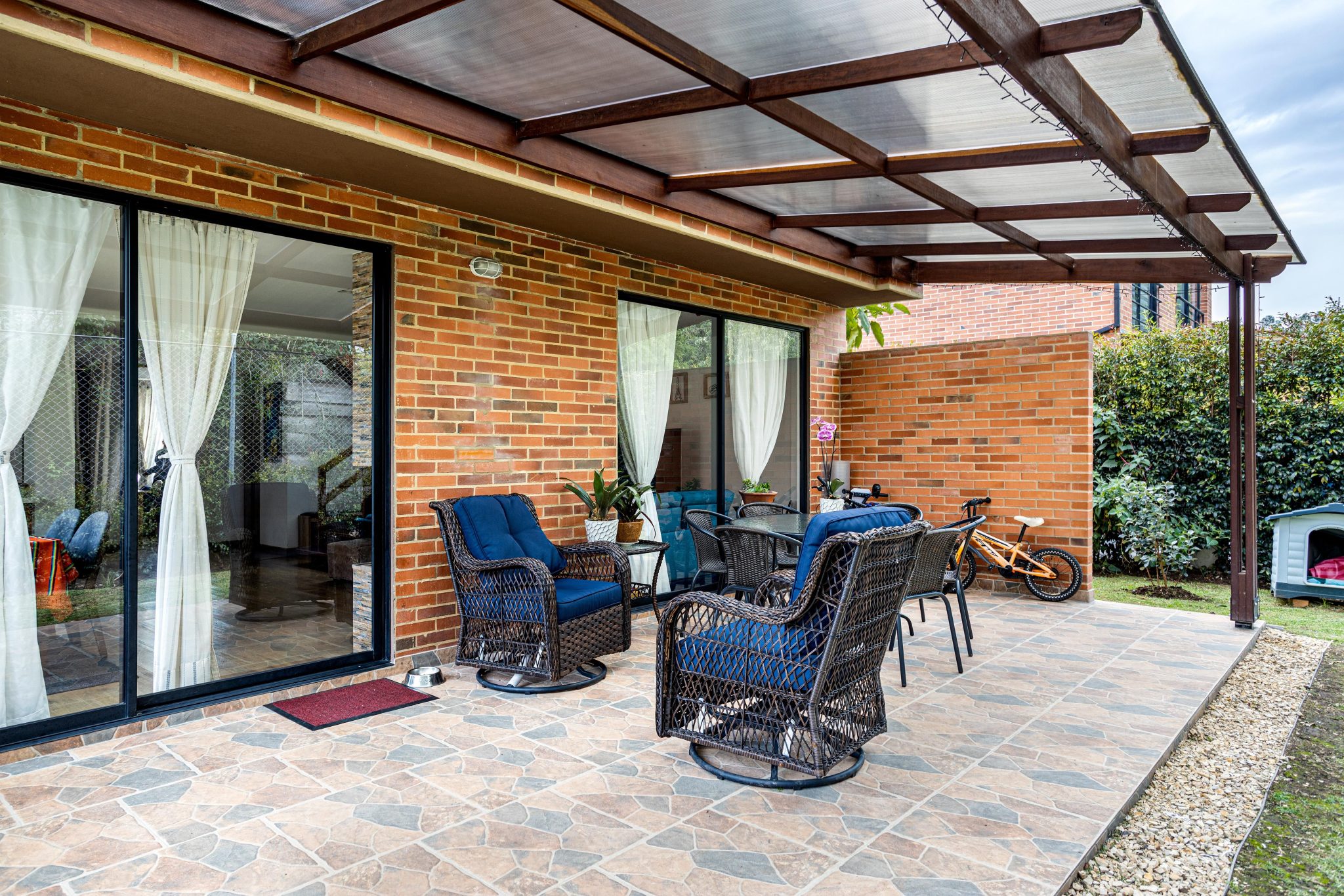 Inviting brick patio with wicker chairs and plants, perfect for relaxation.