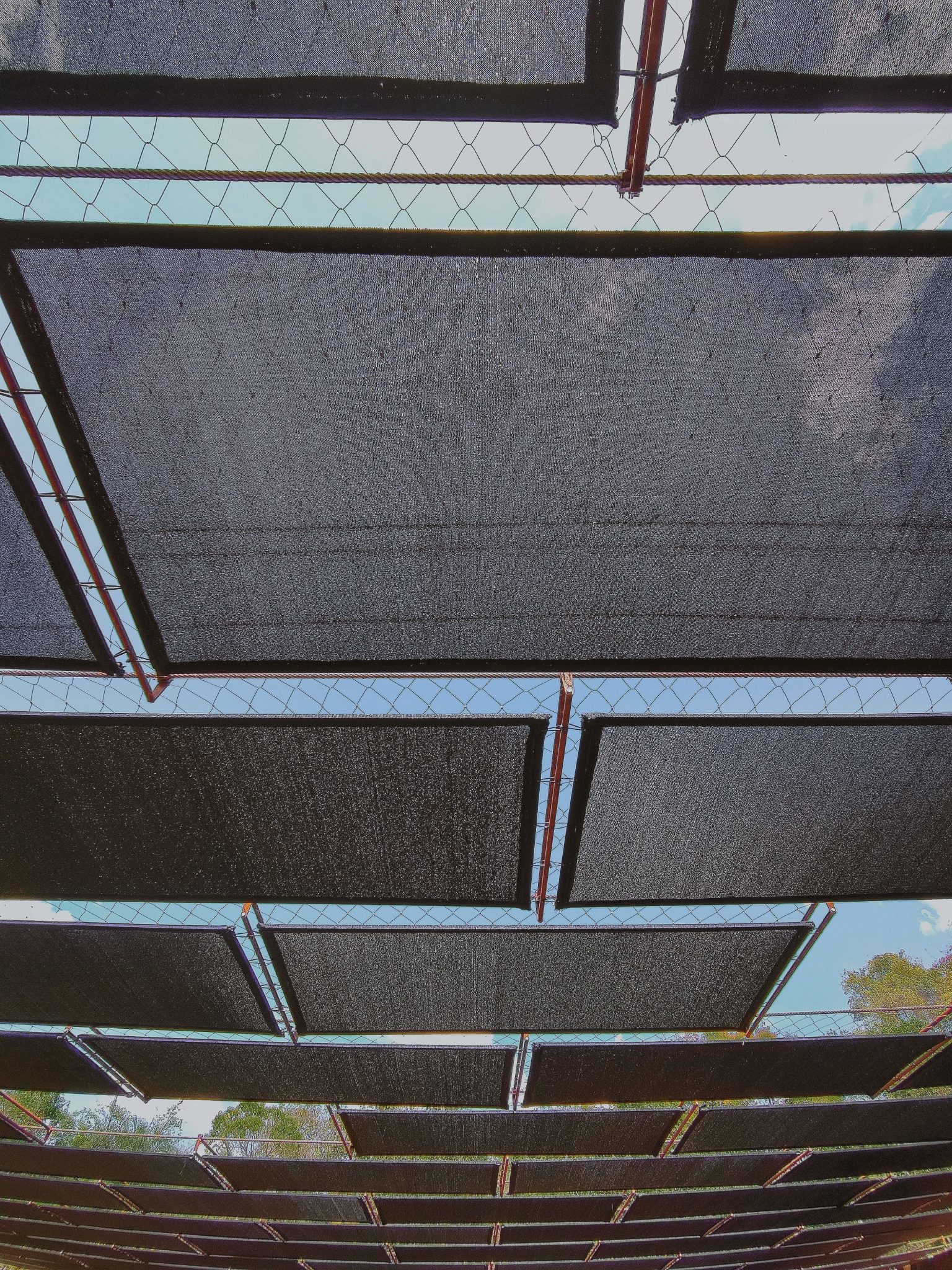 Low angle view of fabric shades creating patterns under a clear sky.