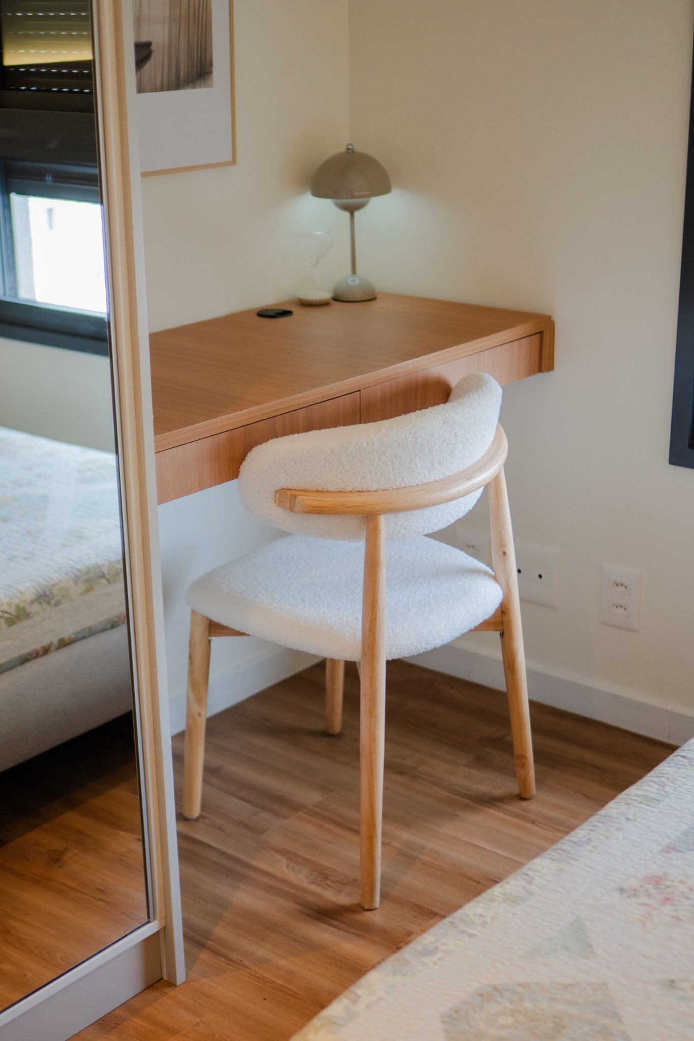 Minimalist home office setup with a wooden desk and white chair, featuring a warm and cozy atmosphere.
