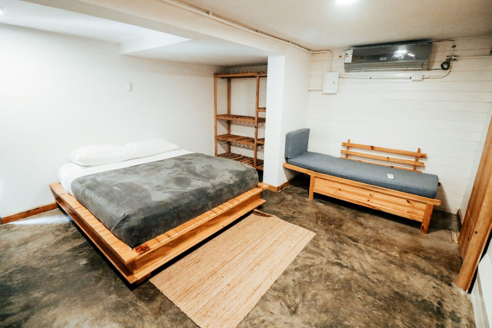 Minimalist modern bedroom with wooden furniture and concrete floor.