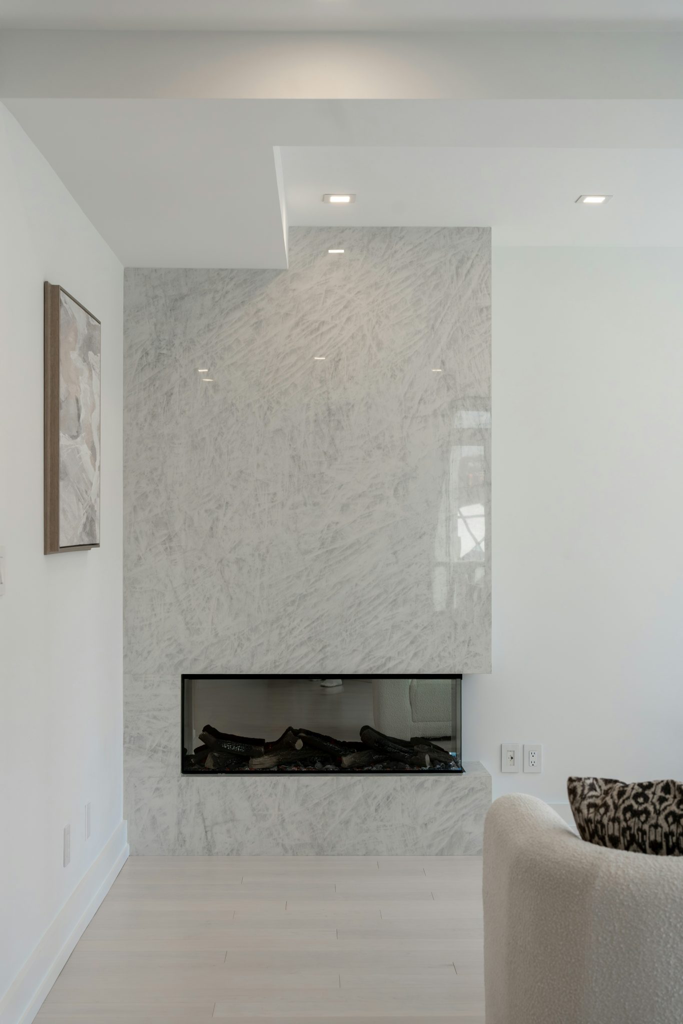 Modern fireplace with white marble surround in a minimalist room.