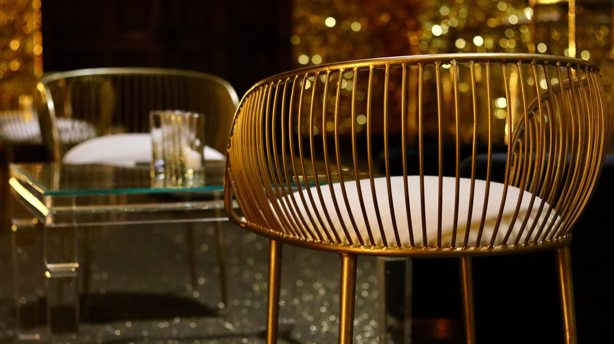 Modern gold armchair and glass table with a luxurious and elegant setting, perfect for upscale interiors.