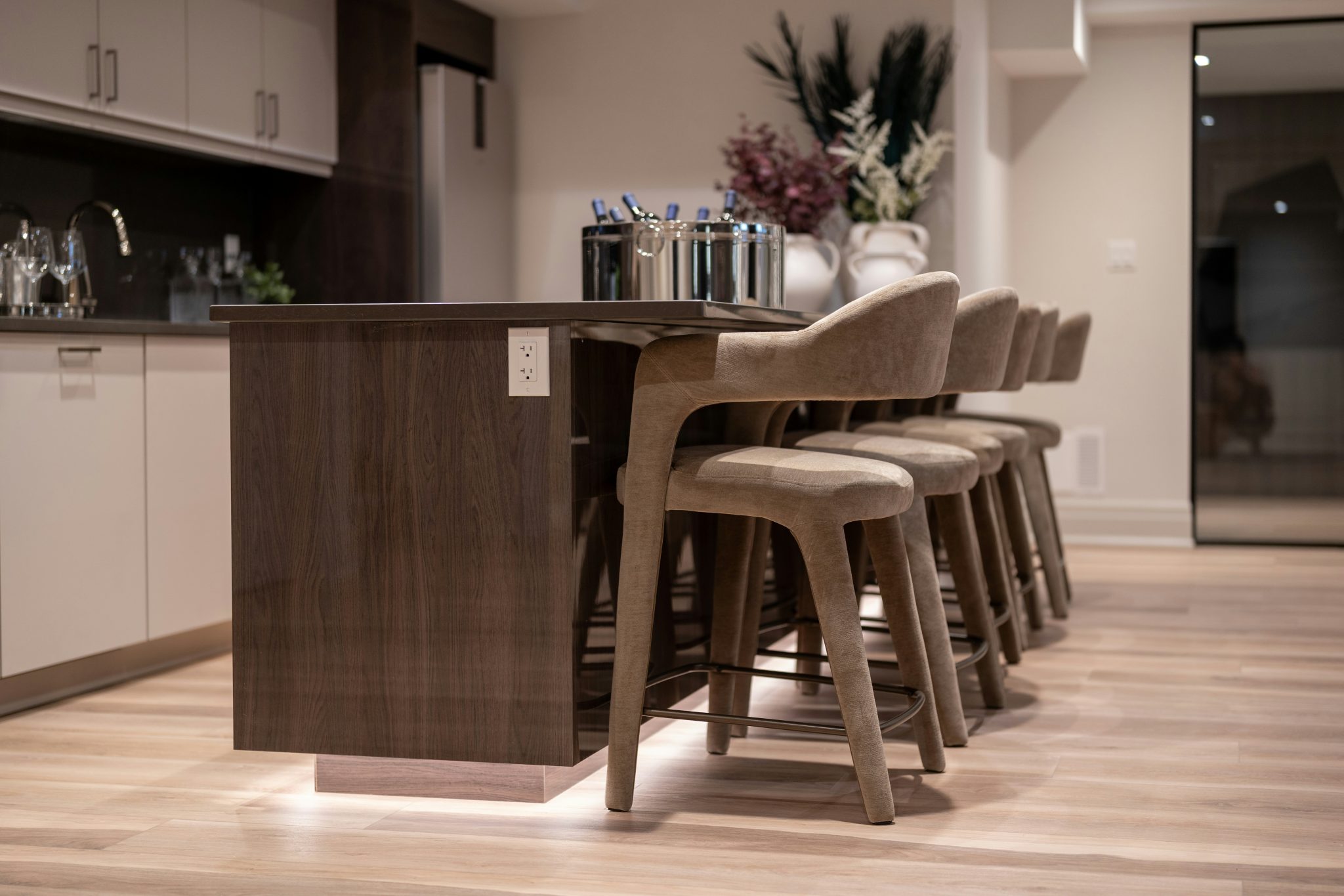 Modern kitchen island with bar stools and decorative vases.