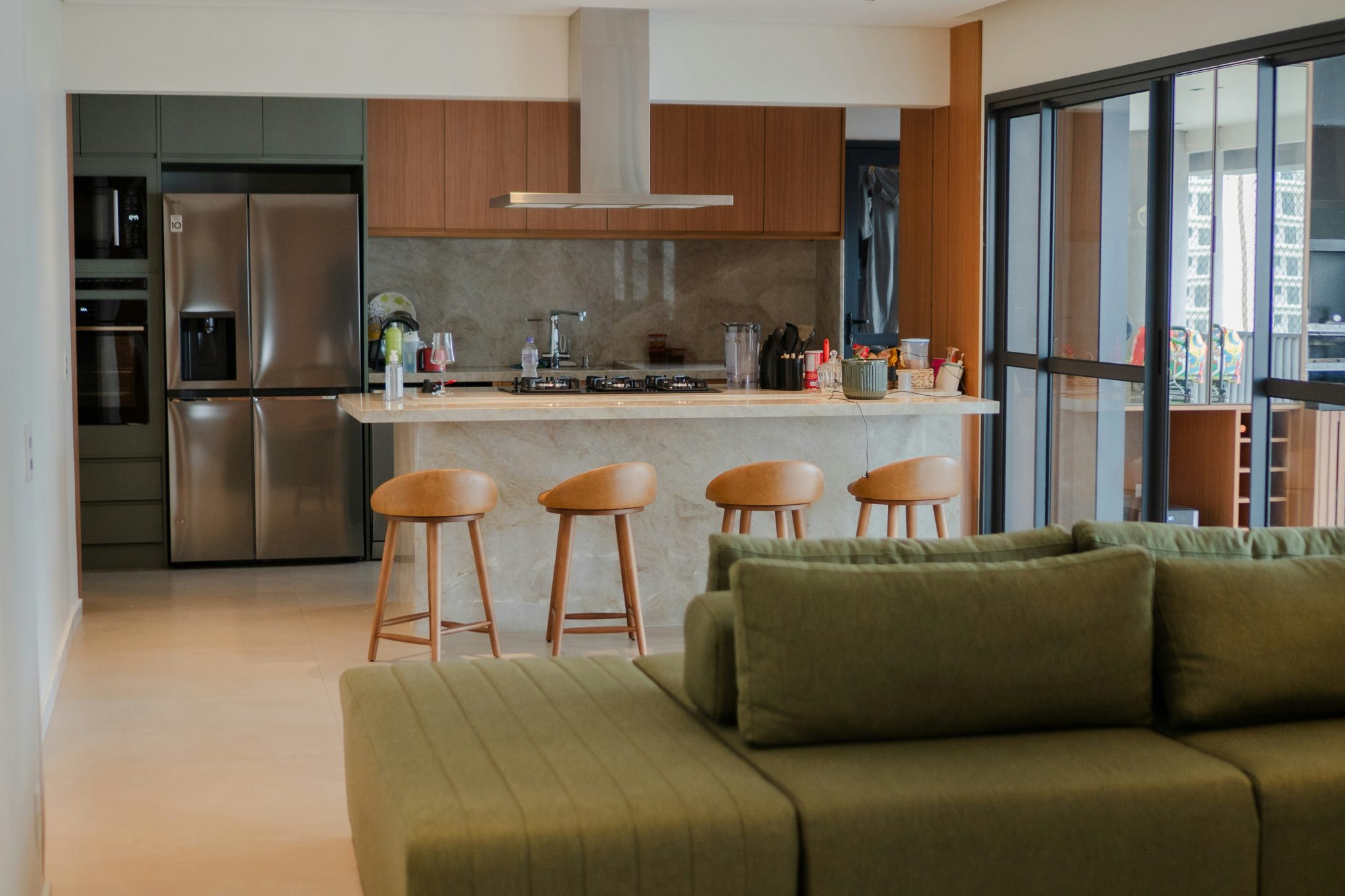 Modern open-plan living room and kitchen with green sofa.