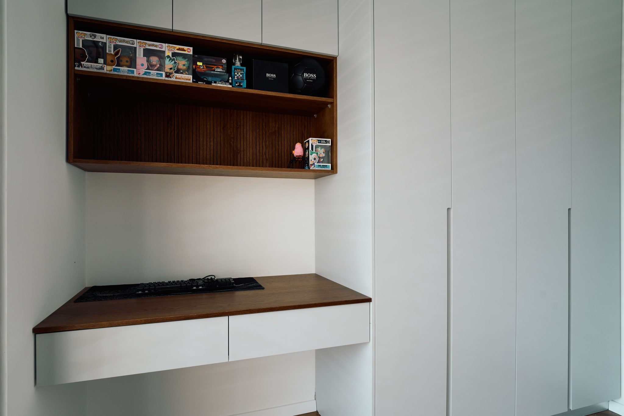 Modern white desk setup with collectibles, ideal for minimalist home office inspiration.