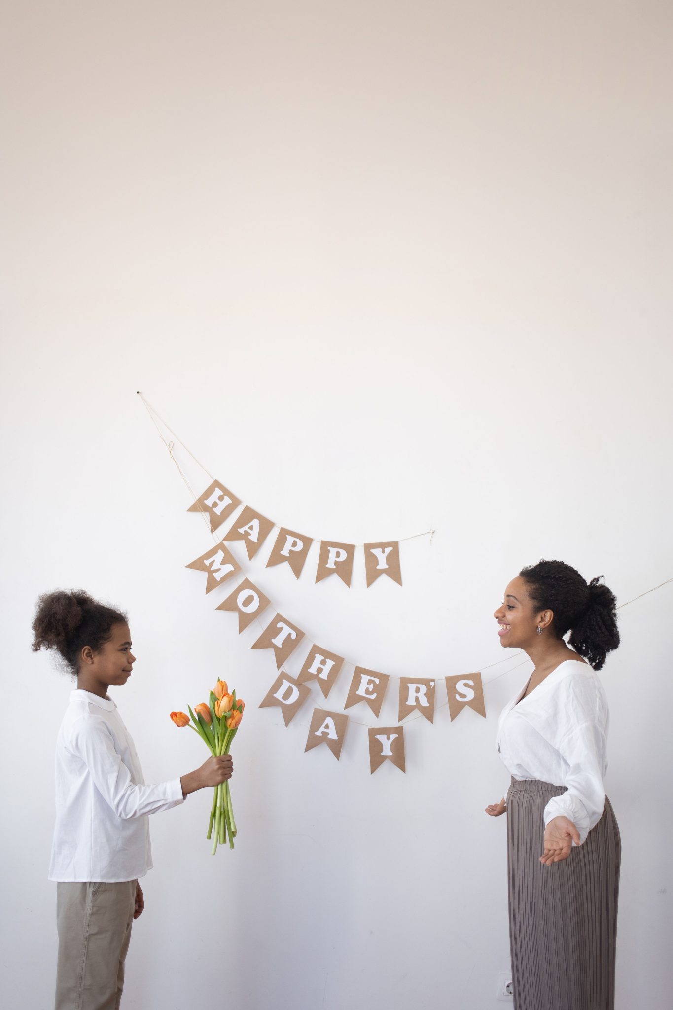 Mother and daughter celebrating Mother's Day with tulips and decor indoors.