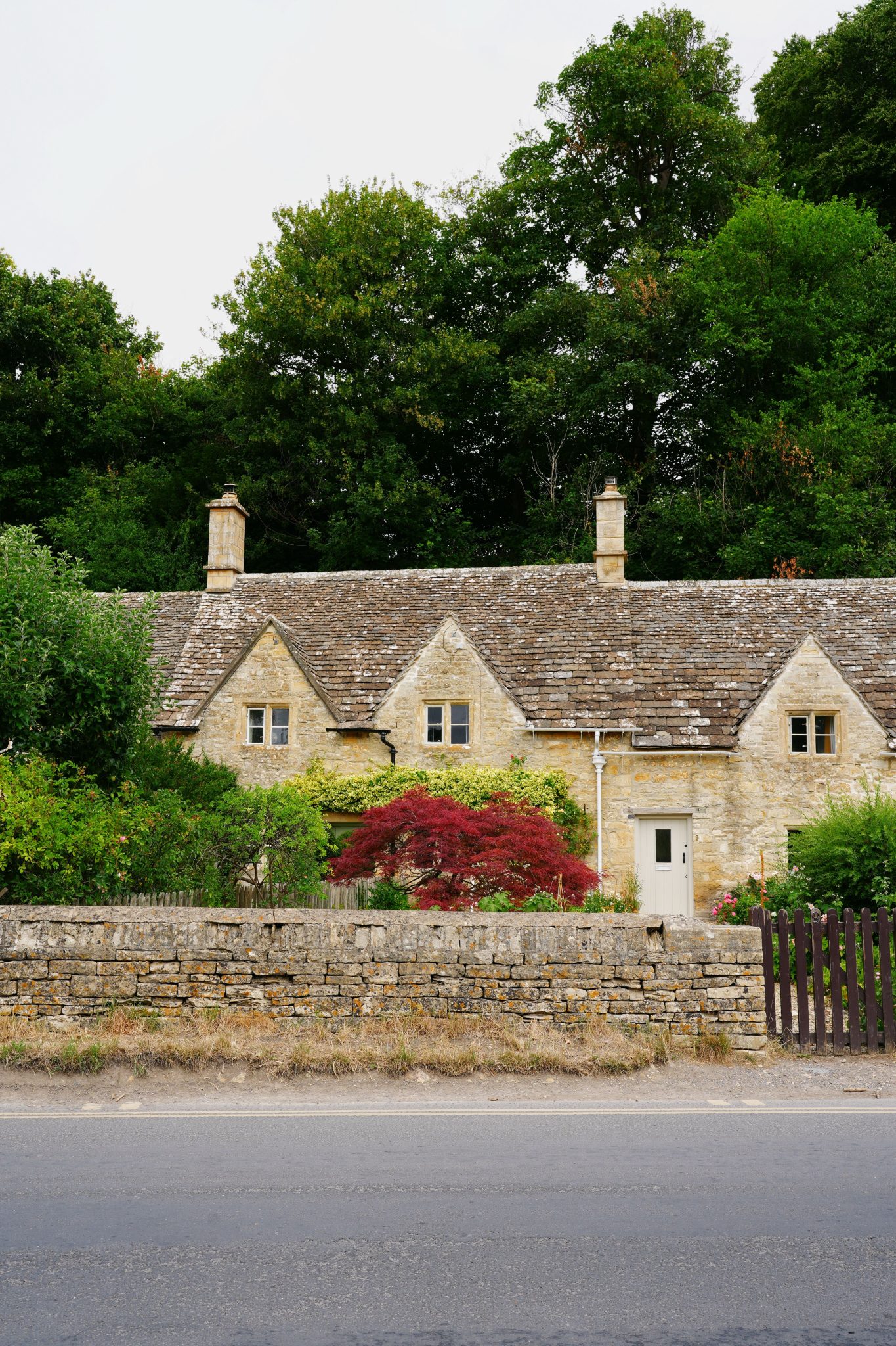 Picturesque stone cottages in the Cotswolds with lush greenery and classic architecture.