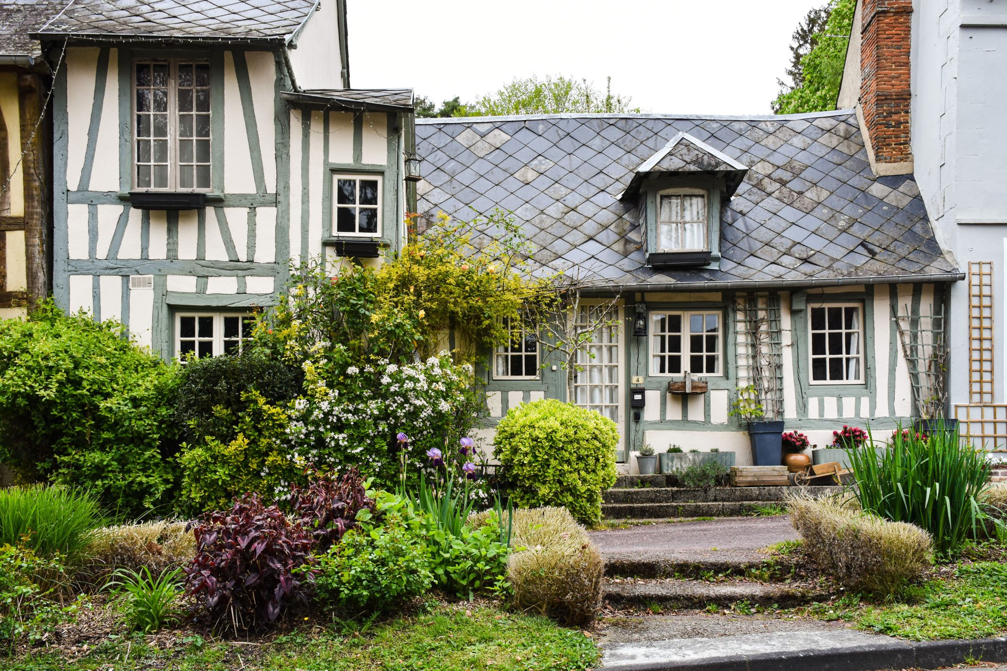 Quaint half-timbered house in Normandy surrounded by a vibrant garden.