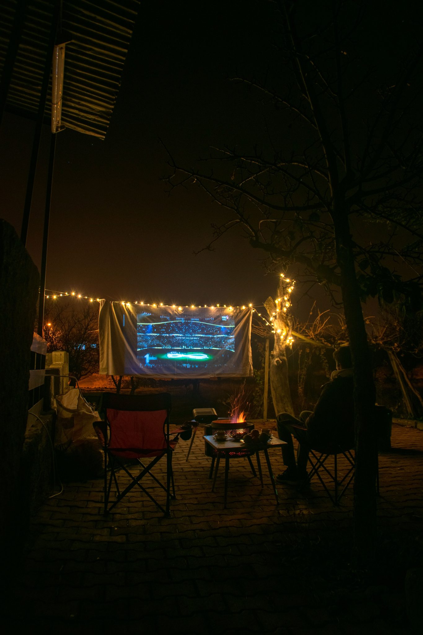 Relaxing outdoor movie night setup with projection screen and campfire ambiance.