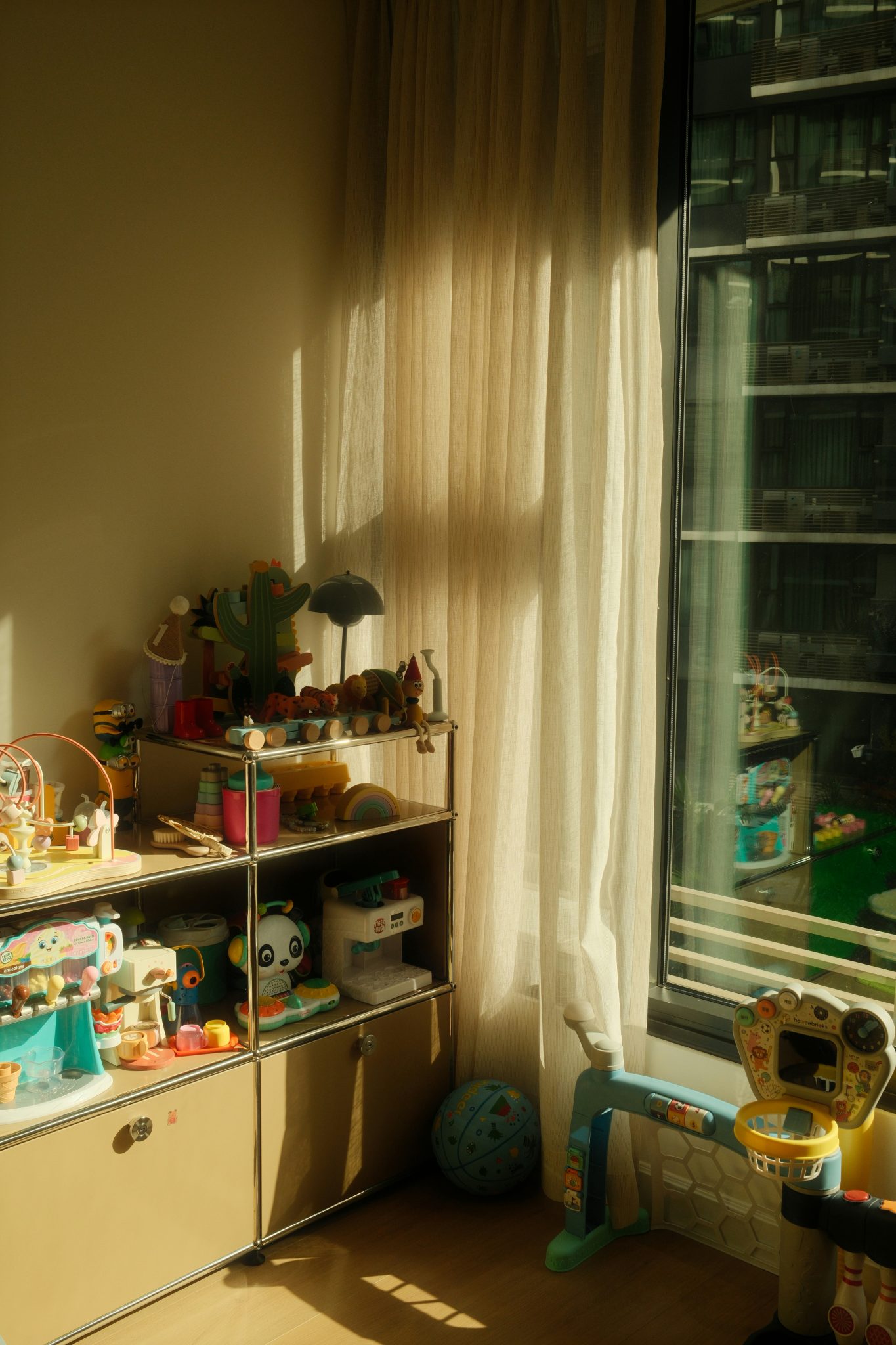Room with sunlight, shelves of toys, and children's play items.