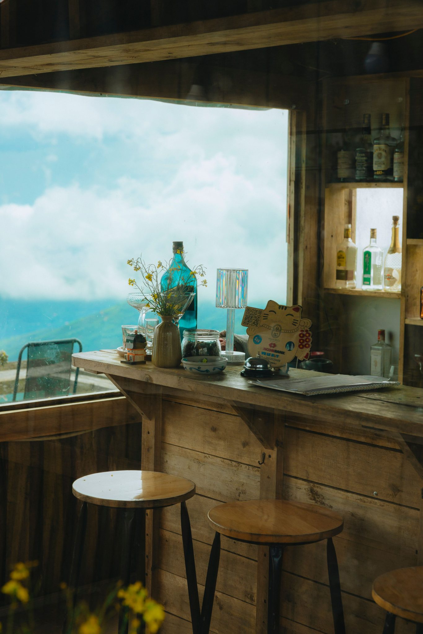 Rustic indoor bar with wooden stools and mountain view, perfect for serene relaxation.