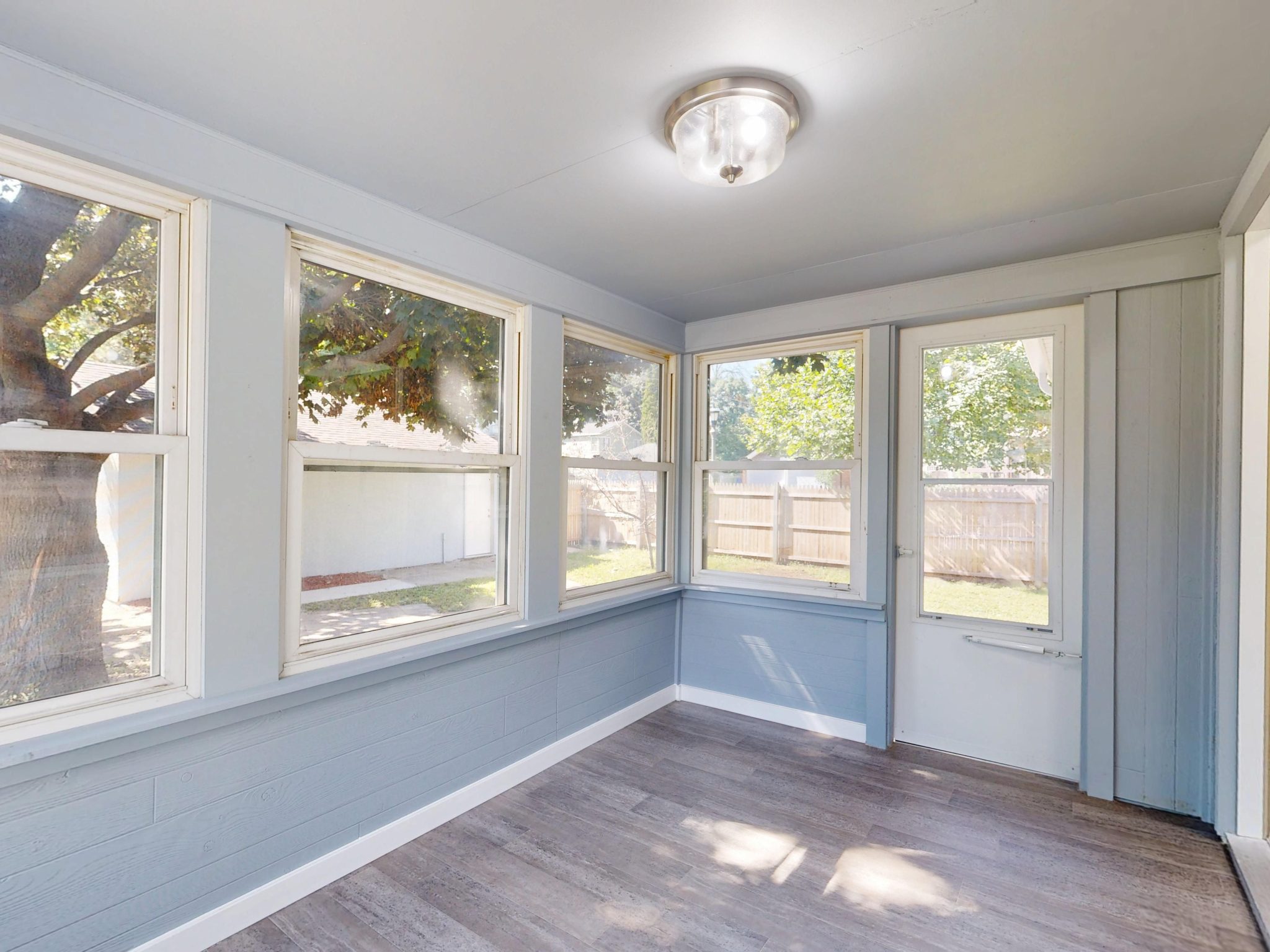 Spacious sunroom with large windows, natural light, and modern flooring.