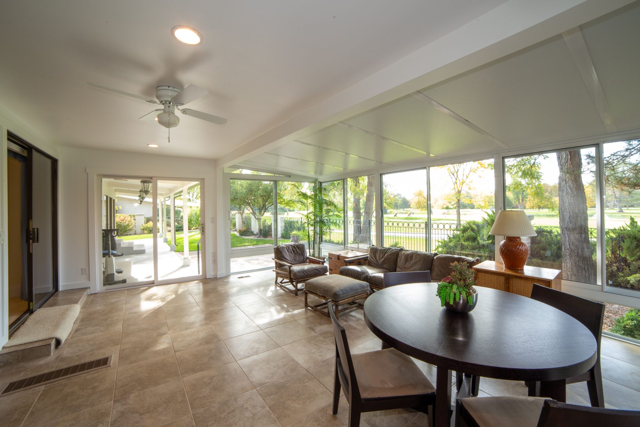 Spacious sunroom with modern interior and large glass windows revealing a scenic garden view.