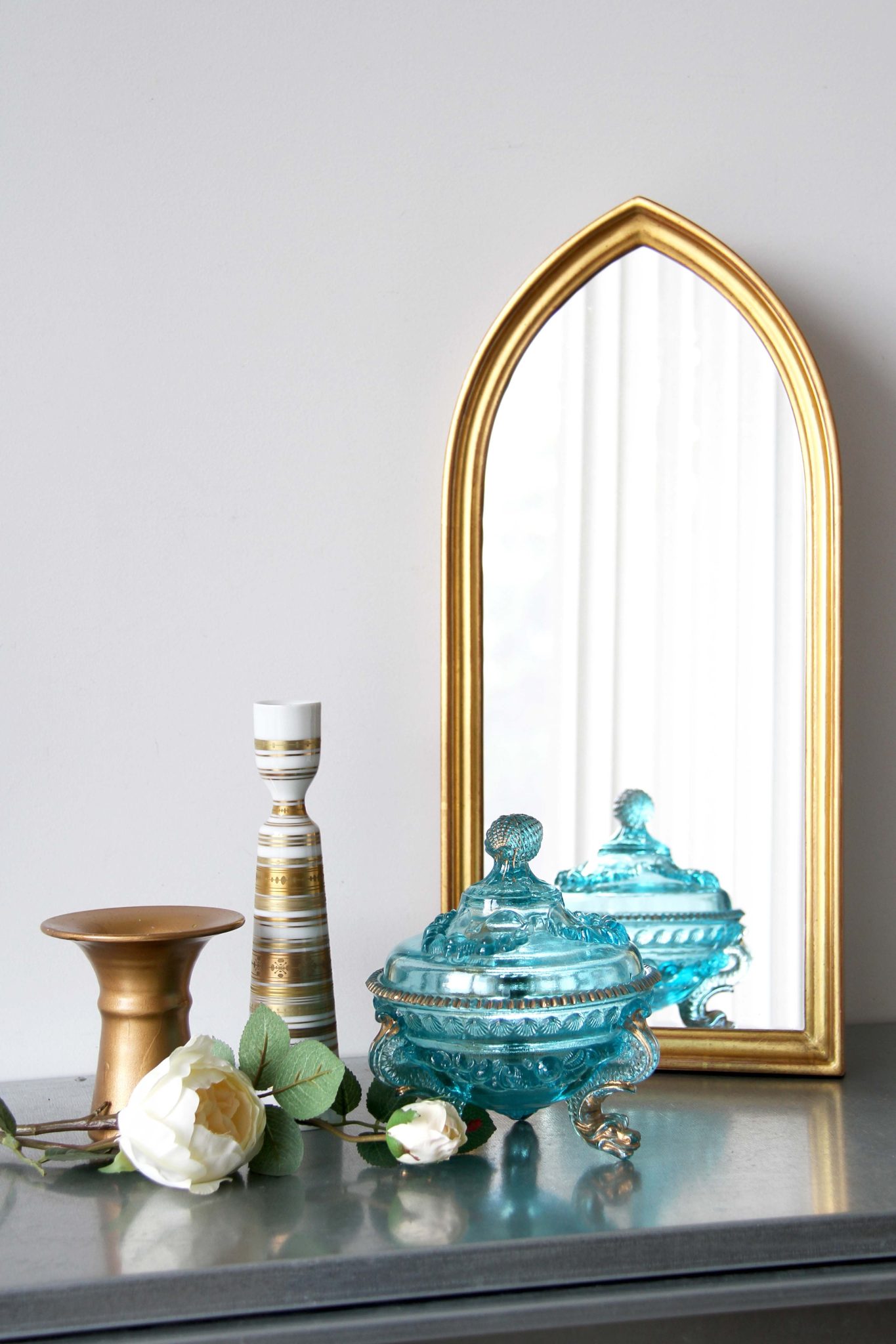 Stylish decor setup with golden mirror and blue glass bowl on table.