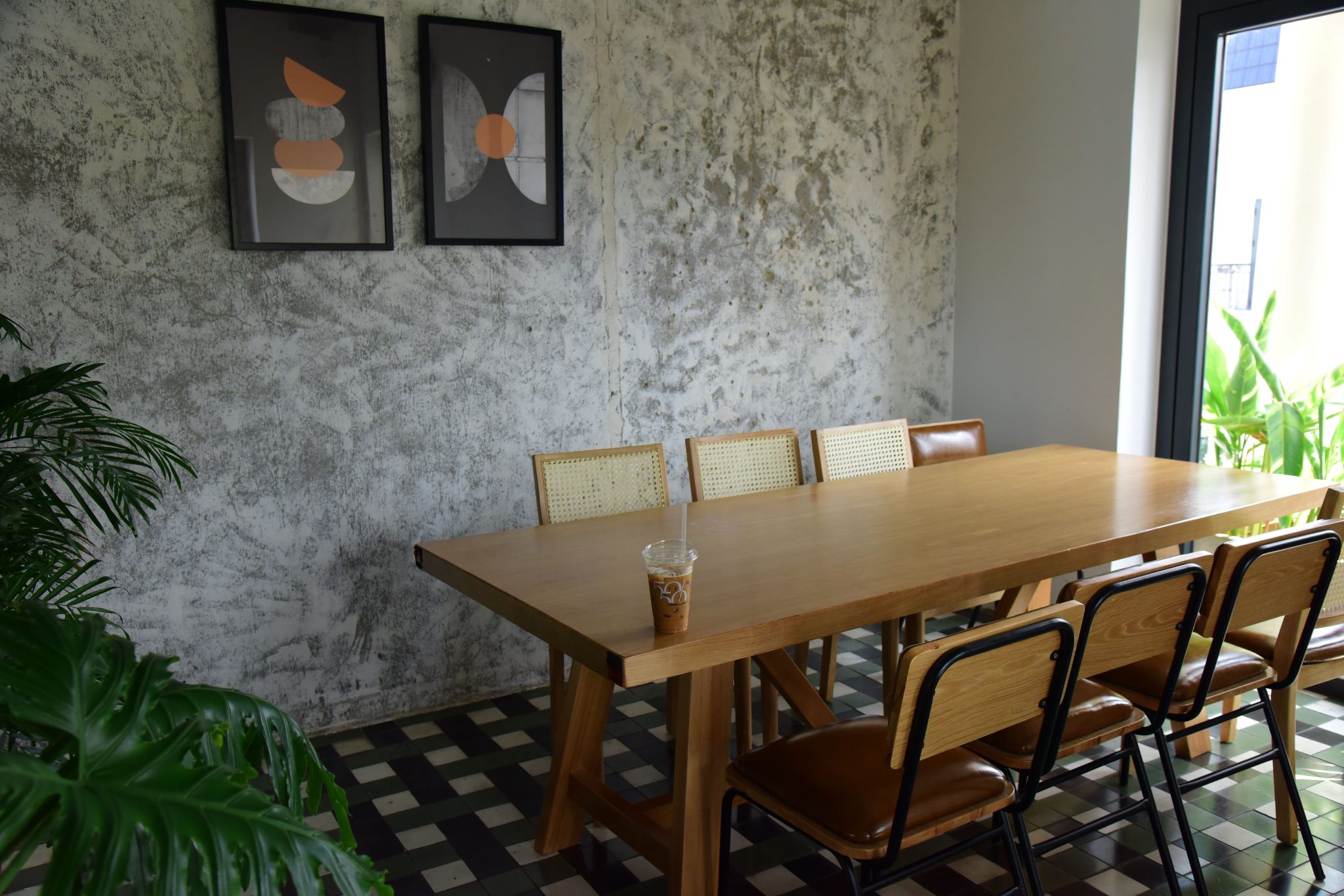 Stylish dining room with a wooden table, chairs, and abstract wall art in a minimalist setting.