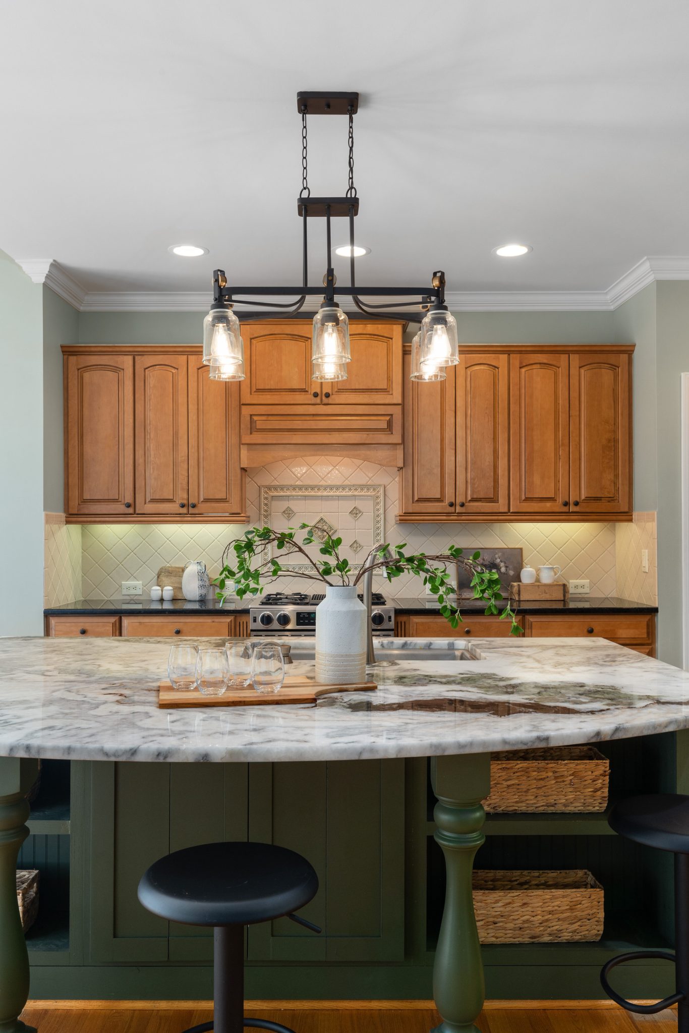 Stylish kitchen featuring a marble top island, wooden cabinets, and modern lighting.