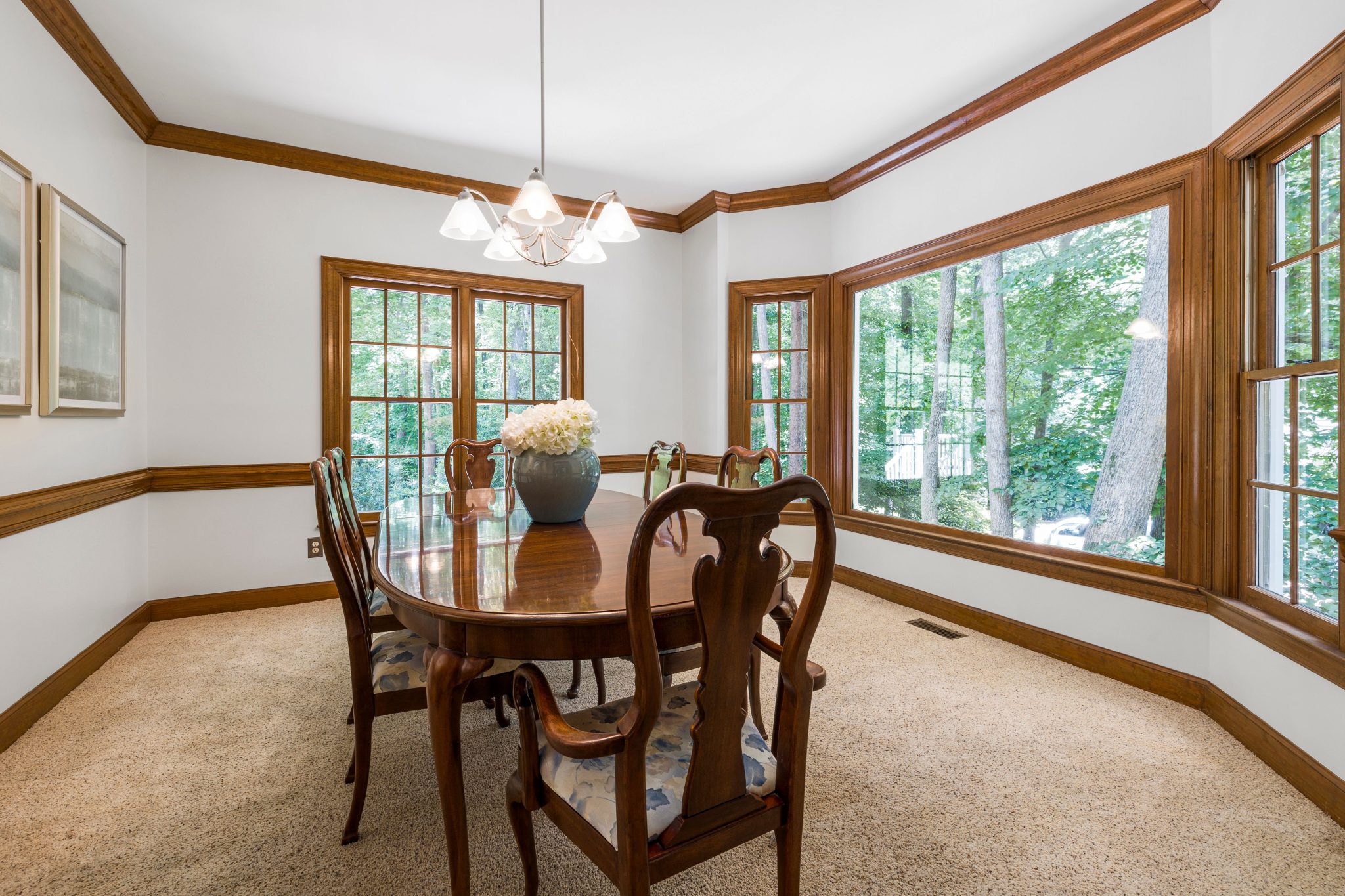 Traditional dining room interior featuring wooden furniture and large picture windows.