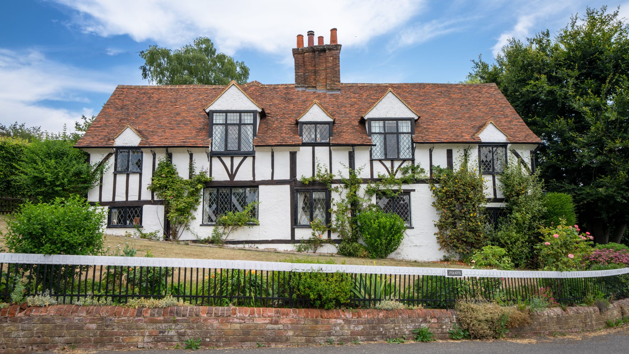 Traditional half-timbered English cottage with lush garden in Latimer, UK.