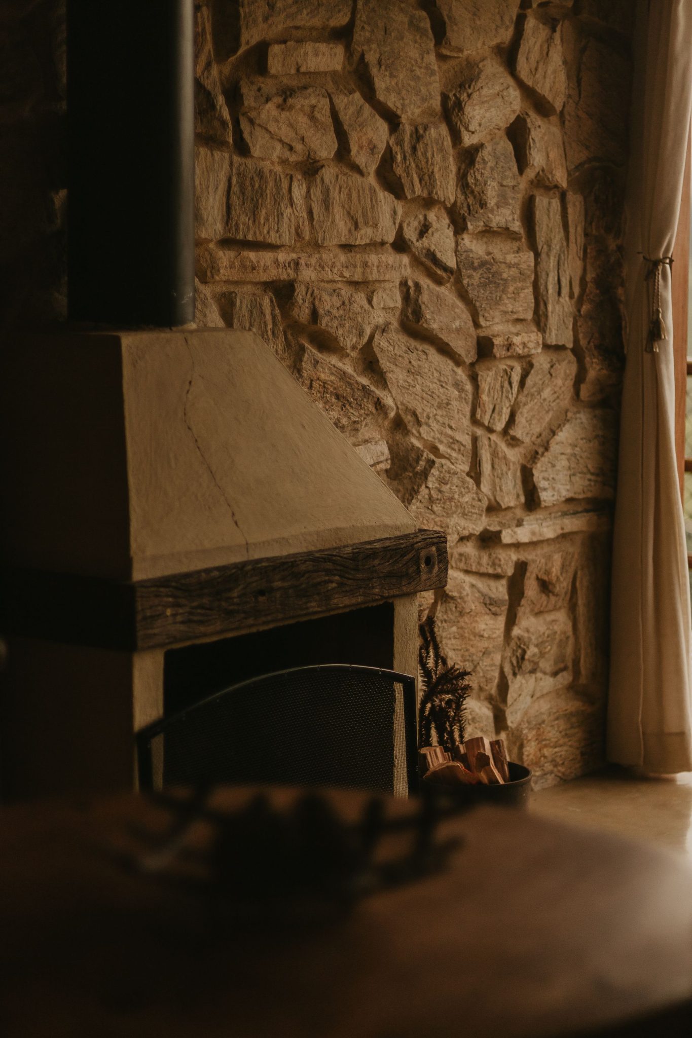 Warm and inviting stone fireplace with wooden accents in a rustic home setting.